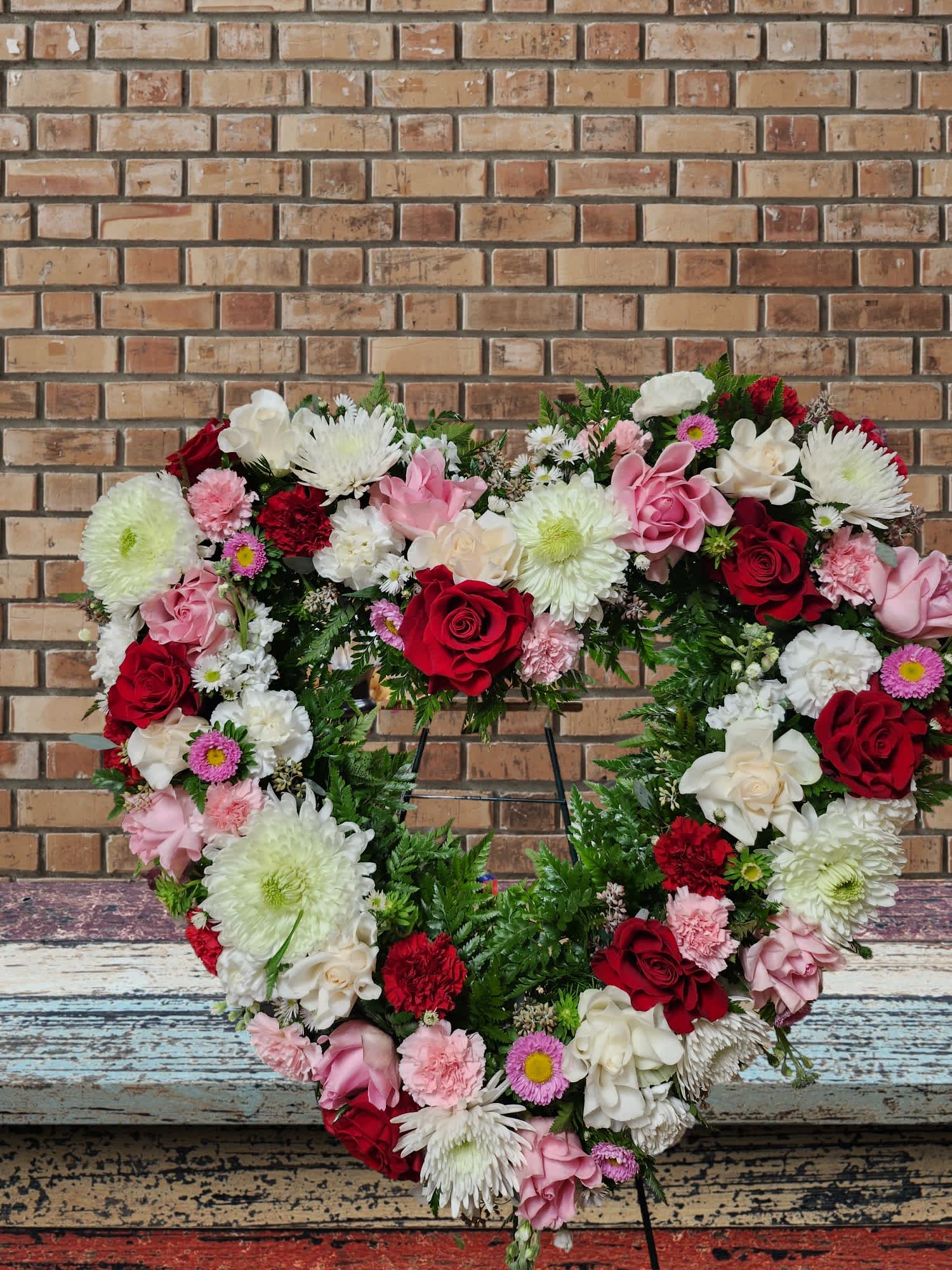 Heart-shaped floral wreath with red, pink, and white blooms