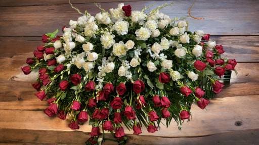 Large arrangement of red and white roses on a wooden surface