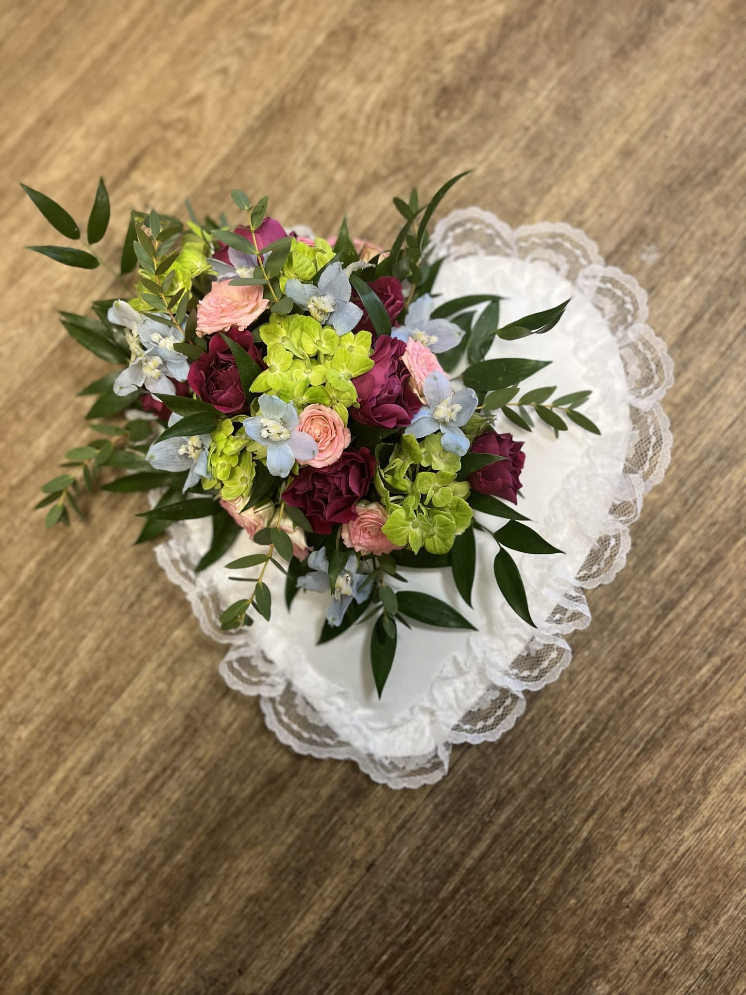 Bouquet of pink, burgundy, and lime flowers on white lace fabric