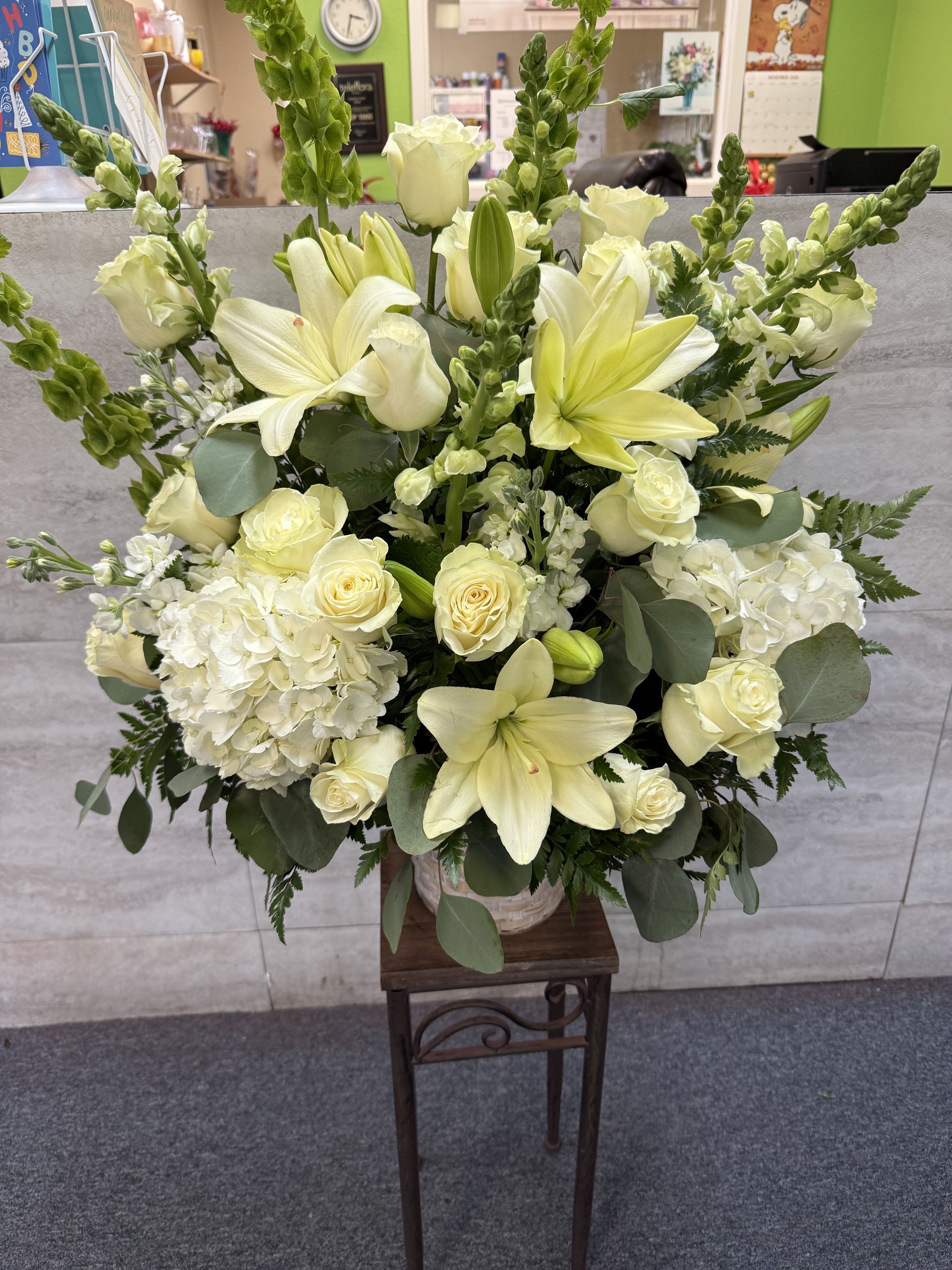 White lilies and roses arranged in a tall vase with greenery