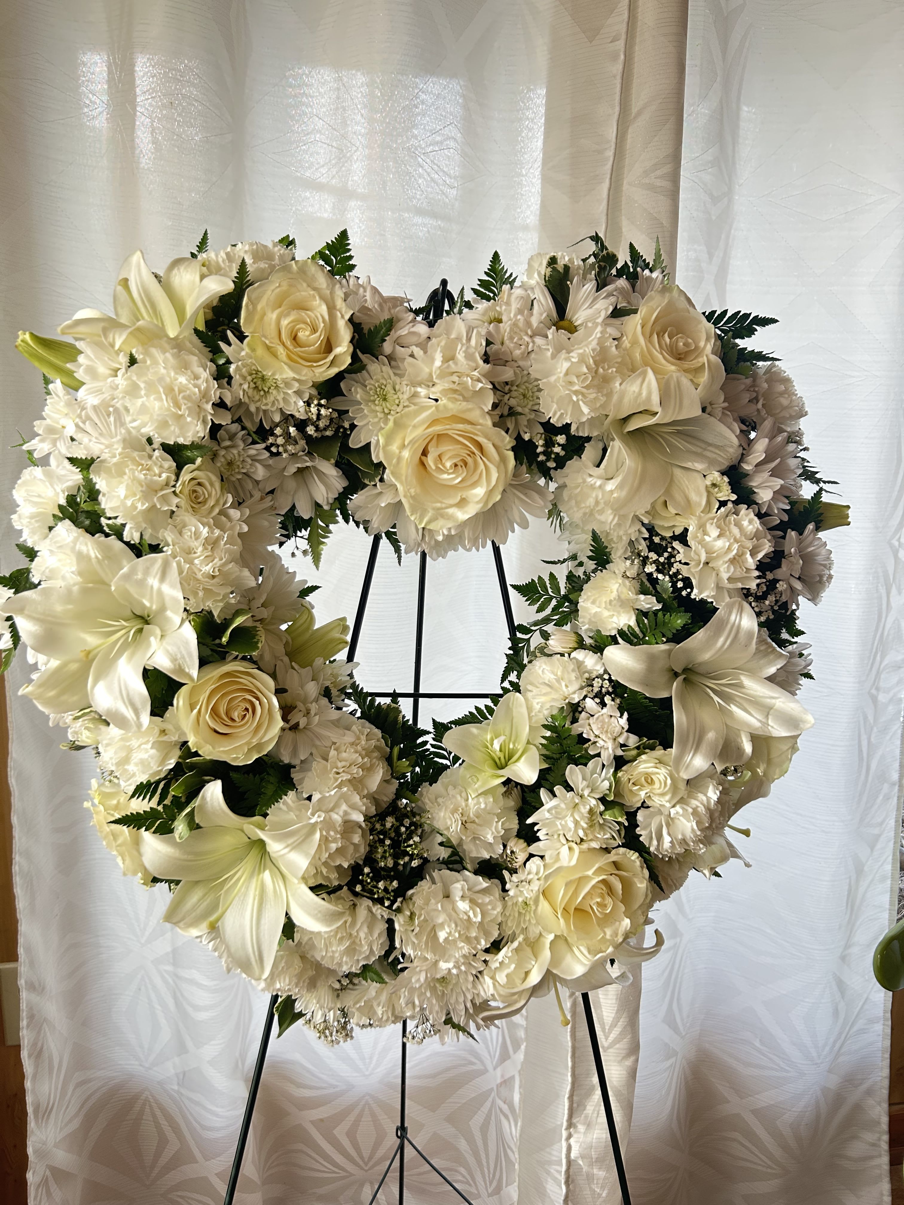 Cream floral heart wreath on a black stand