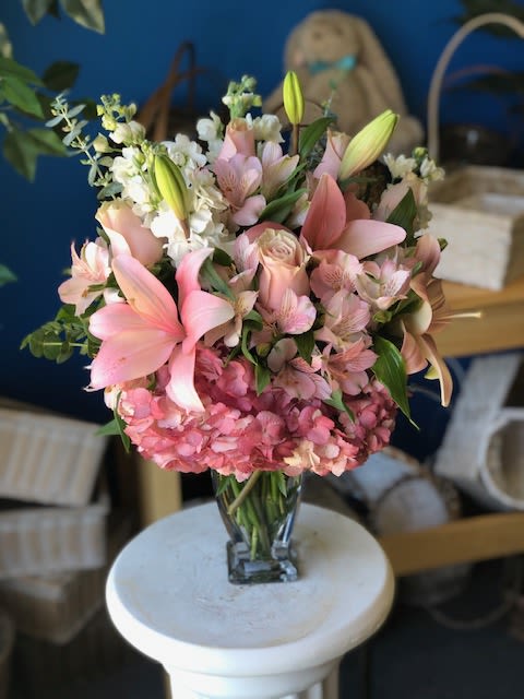 Perfect Pink  - (ONE-SIDED) This arrangement features soft pink lilies, blush roses, delicate alstroemeria, and lush pink hydrangea, accented with fresh white stock and greenery. The mix of gentle textures and romantic tones creates a full, elegant look that feels both timeless and heartfelt. 