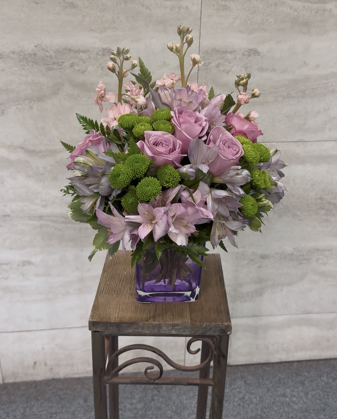 Pink roses and lavender flowers arranged in a purple vase