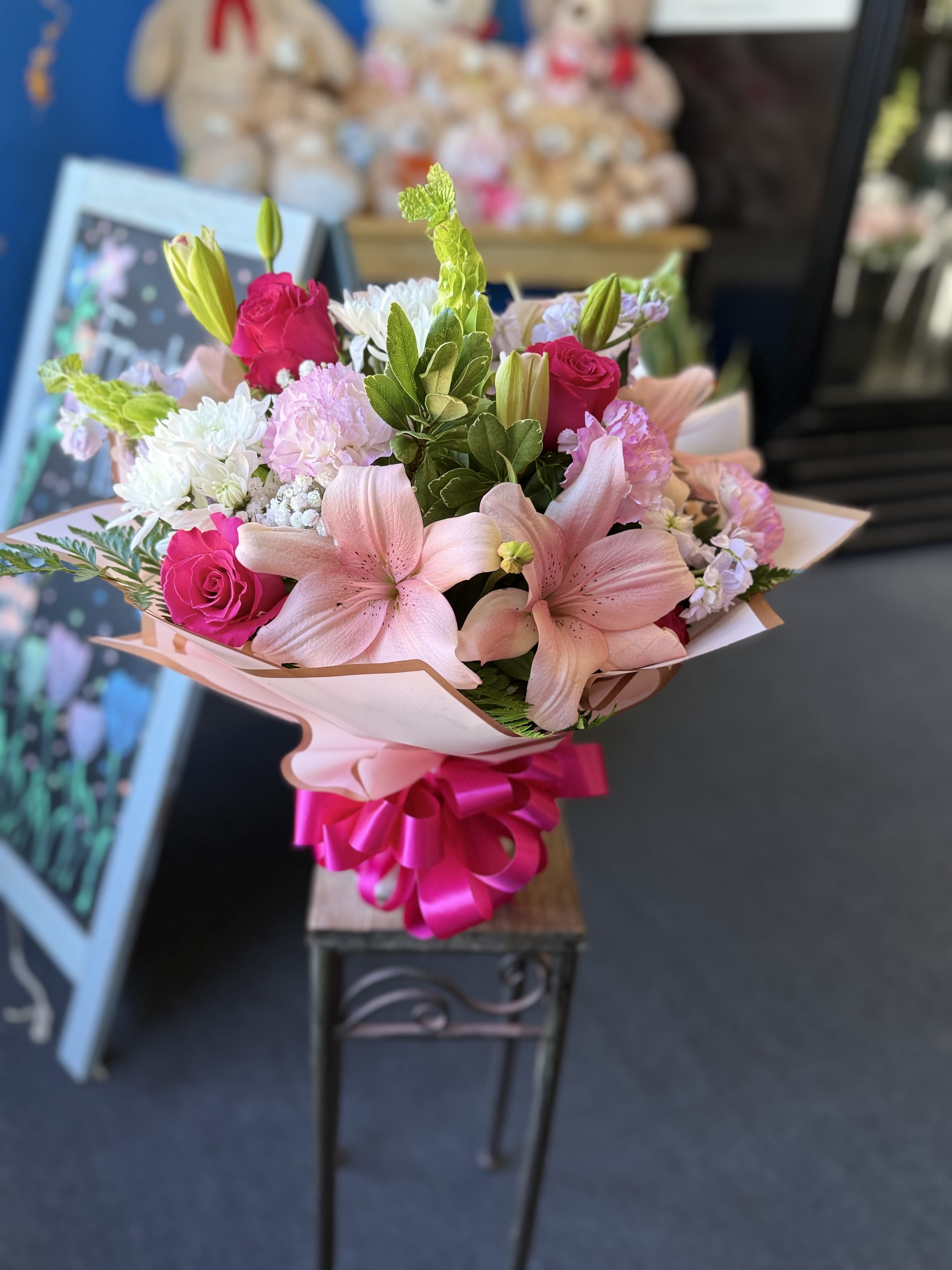 Pink Petals - Pink and white lilies, hot-pink roses, chrysanthemums and carnations with green accents and lavender fillers, wrapped in pale paper with a bright satin ribbon-cheerful, romantic, perfect for celebrations.