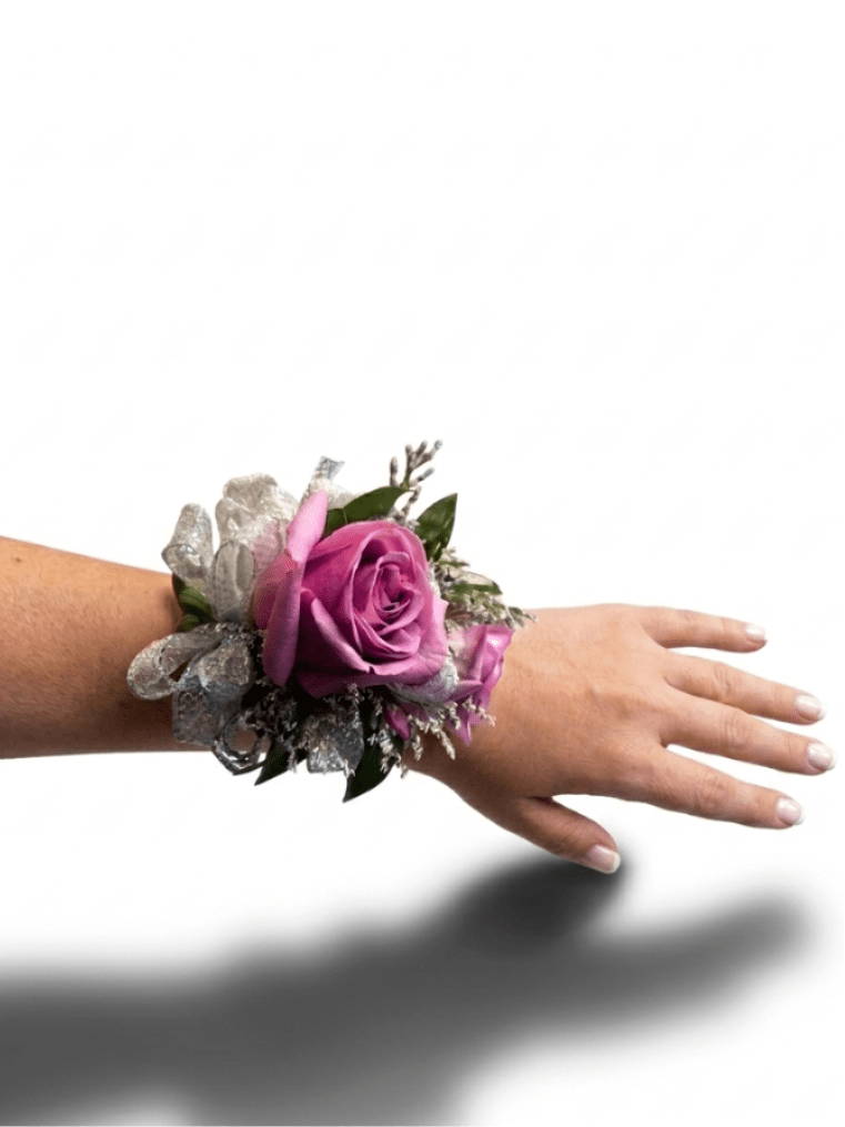 Purple rose wrist corsage with silver ribbon on a person’s arm