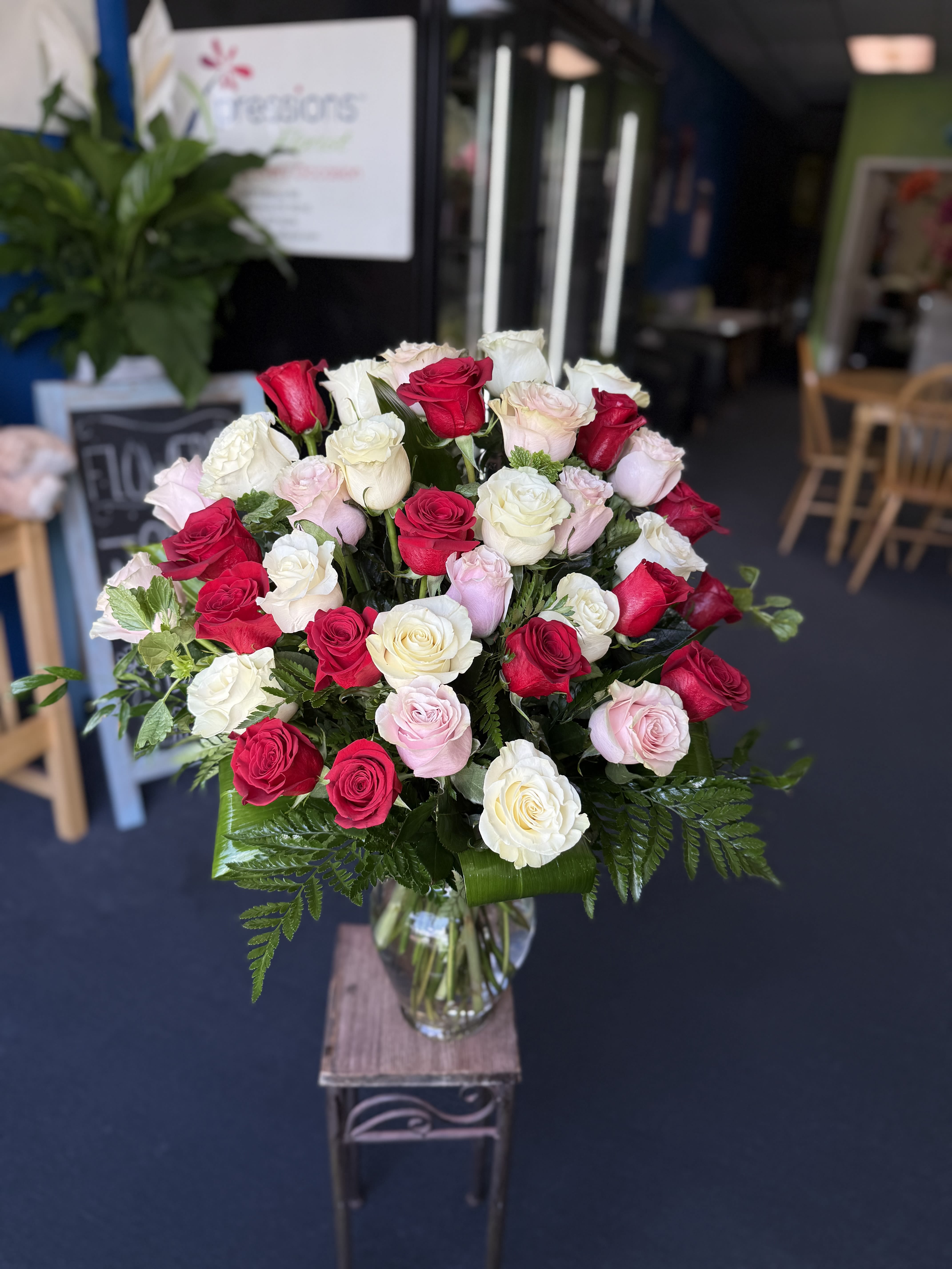 When I Say I Love You - (ALL-ROUND) A 36 full, elegant arrangement of red, white, and light pink roses in a balanced, fan-shaped design, accented with lush green foliage and displayed in a clear glass vase.  