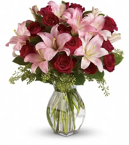 Bouquet of pink lilies and red roses in a clear glass vase