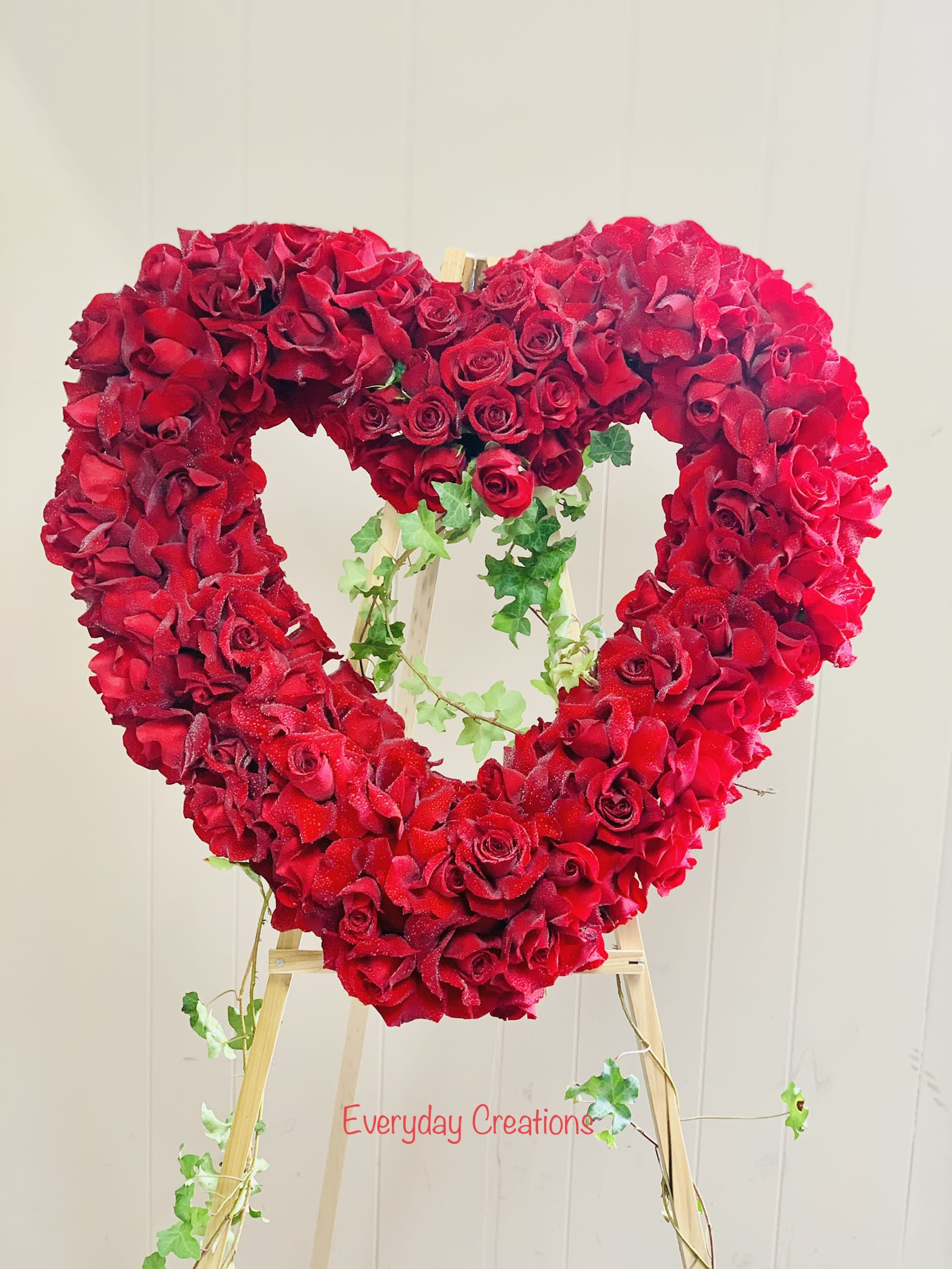 Heart-shaped red rose arrangement on a wooden easel