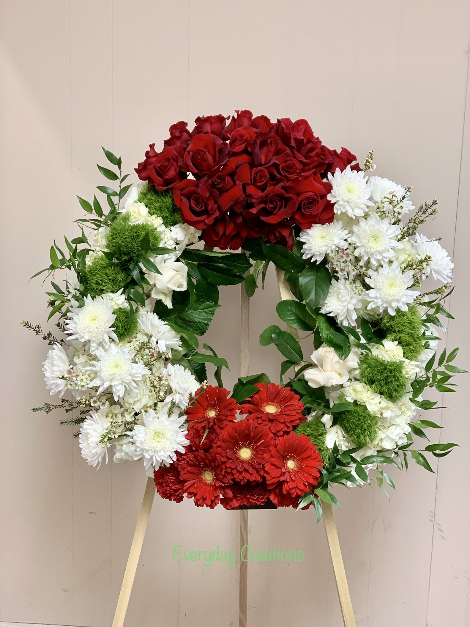 Heart-shaped floral wreath with red roses, white daisies, and red gerberas