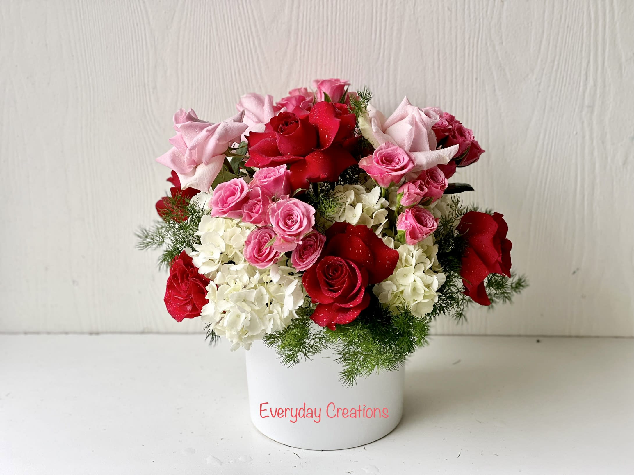 Pink and red roses arranged in a white container