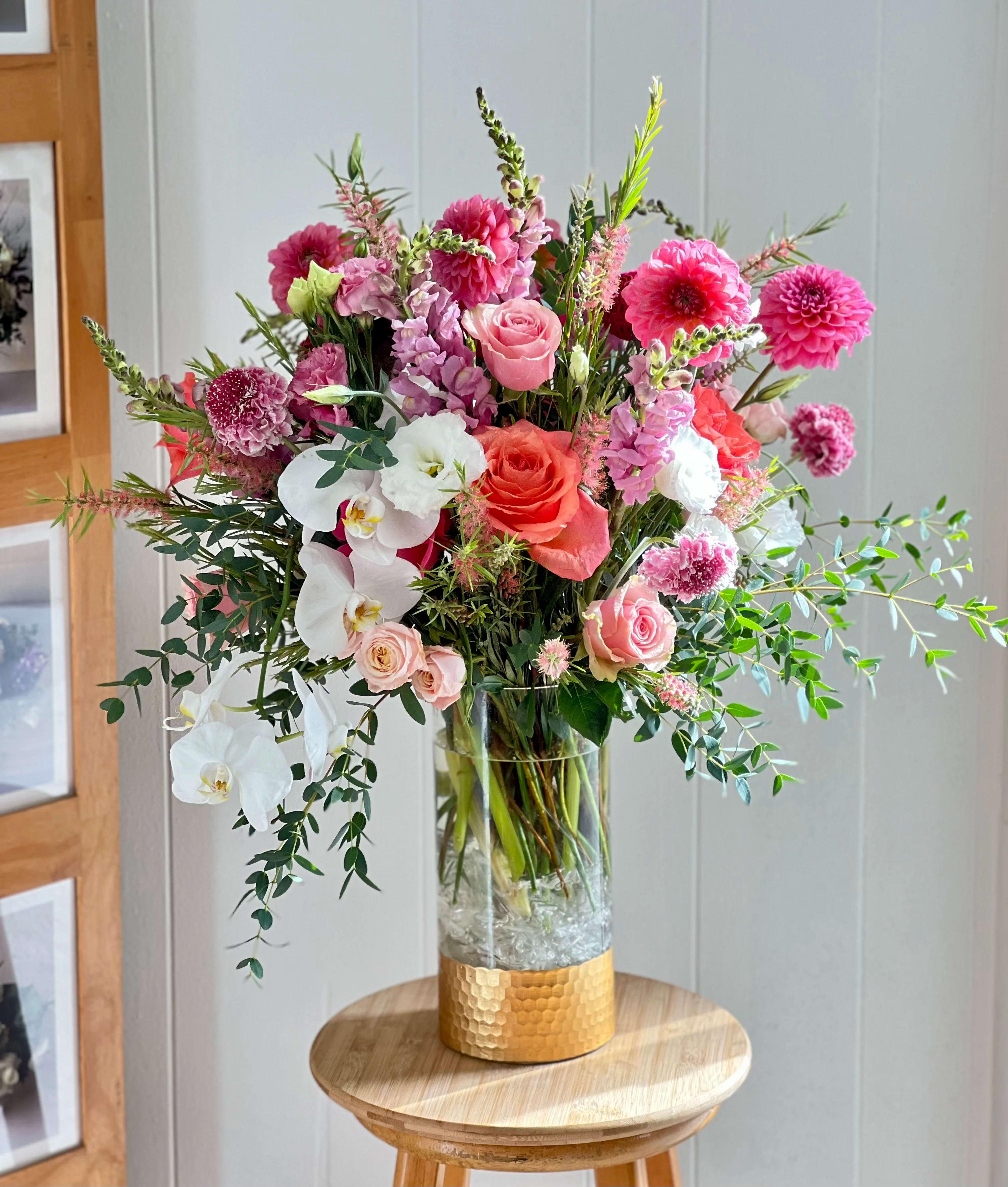 Tall mixed bouquet of pink, white, and coral flowers in a glass vase