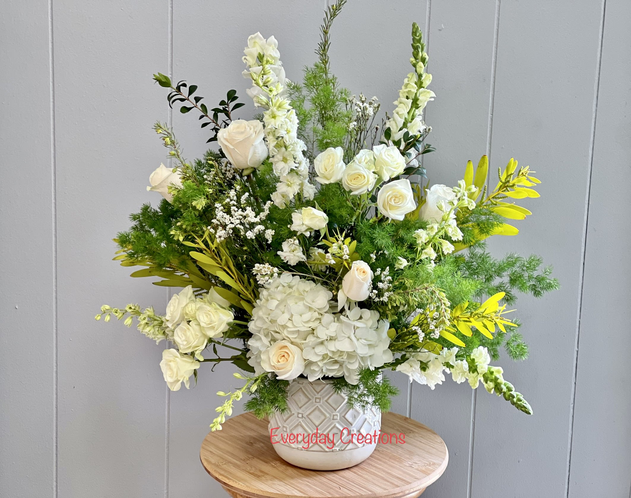SYM08 - Sweet Comfort - An all white tribute, this funeral arrangement is pure and tranquil. Featuring a variety of white flowers and greenery, this design reaches for the sky and evokes a feeling of peace upward and outward. Perfect for sending to the home of someone experiencing loss or to a funeral or memorial service to create a stunning display. 
