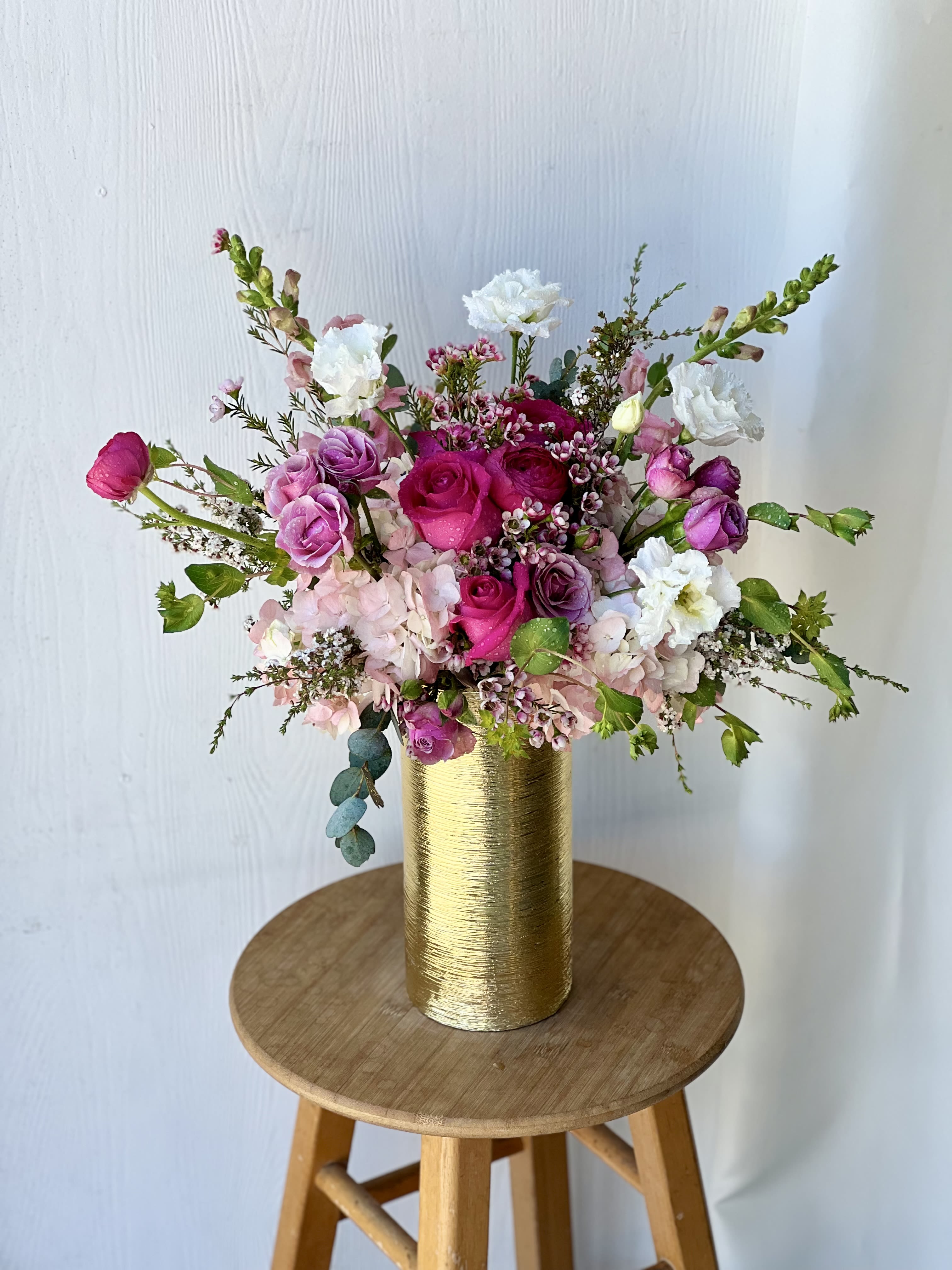 Pink and white floral arrangement in a gold vase