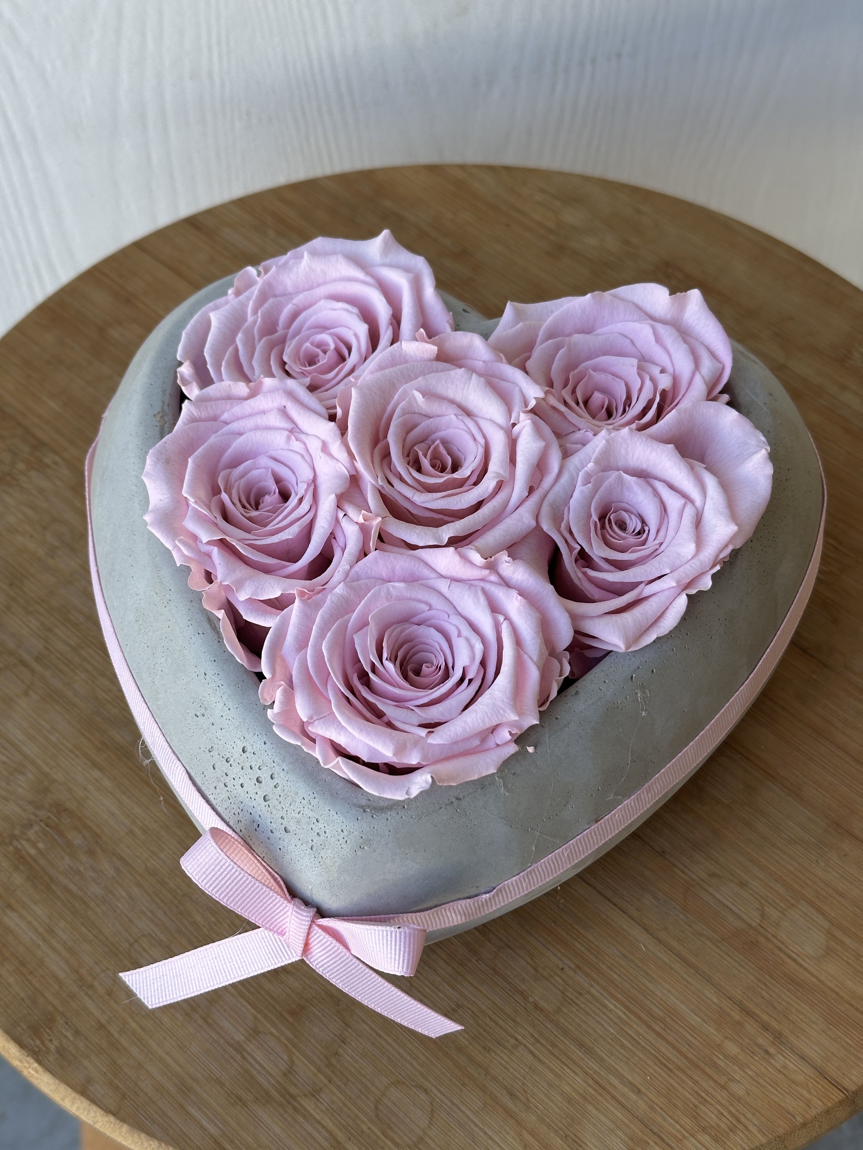 Heart-shaped box of pale pink roses tied with a pink ribbon