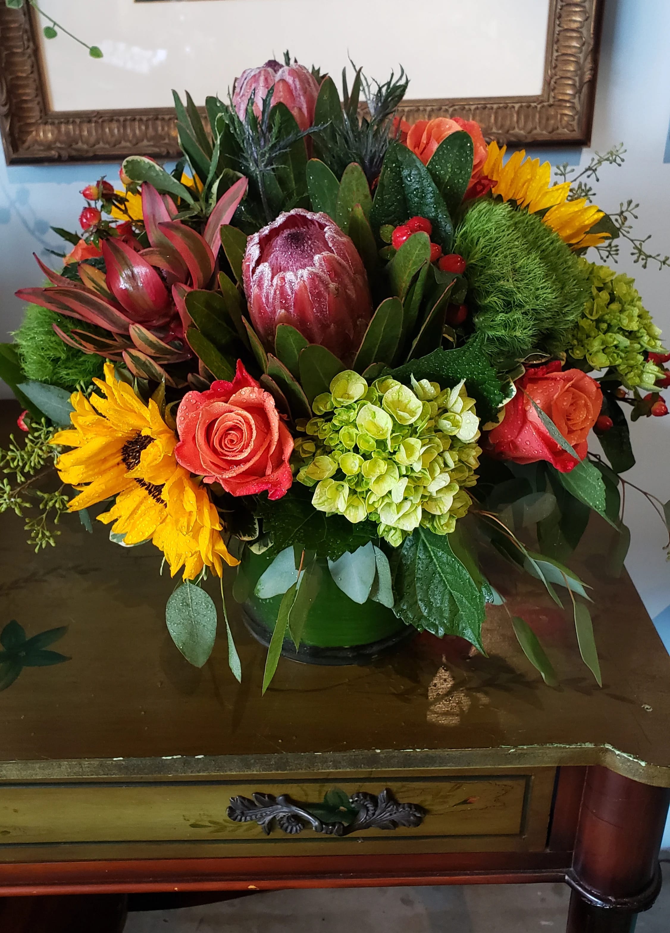 Mixed bouquet with protea, roses, sunflowers, and hydrangea in a vase