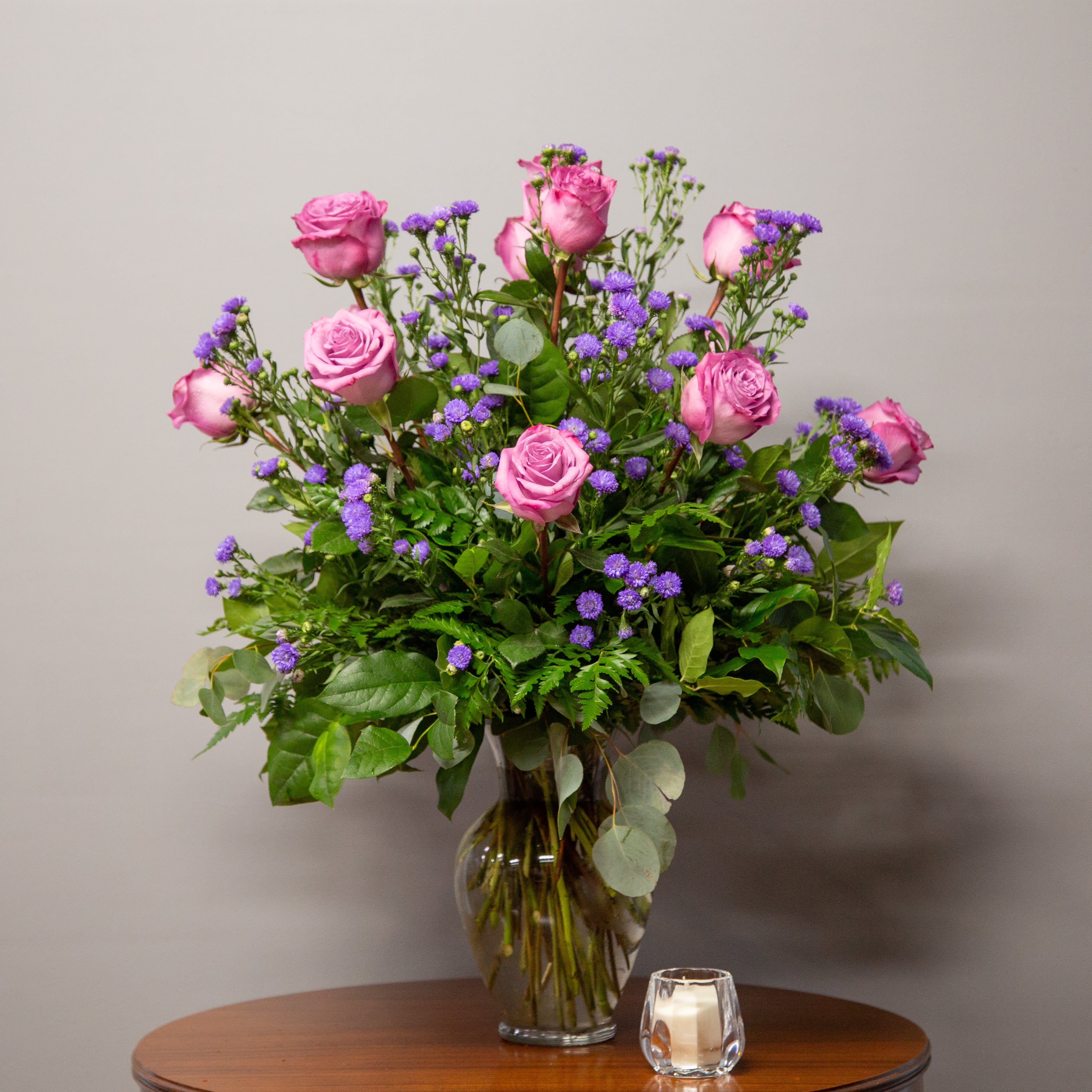 Pink roses and purple filler flowers in a glass vase