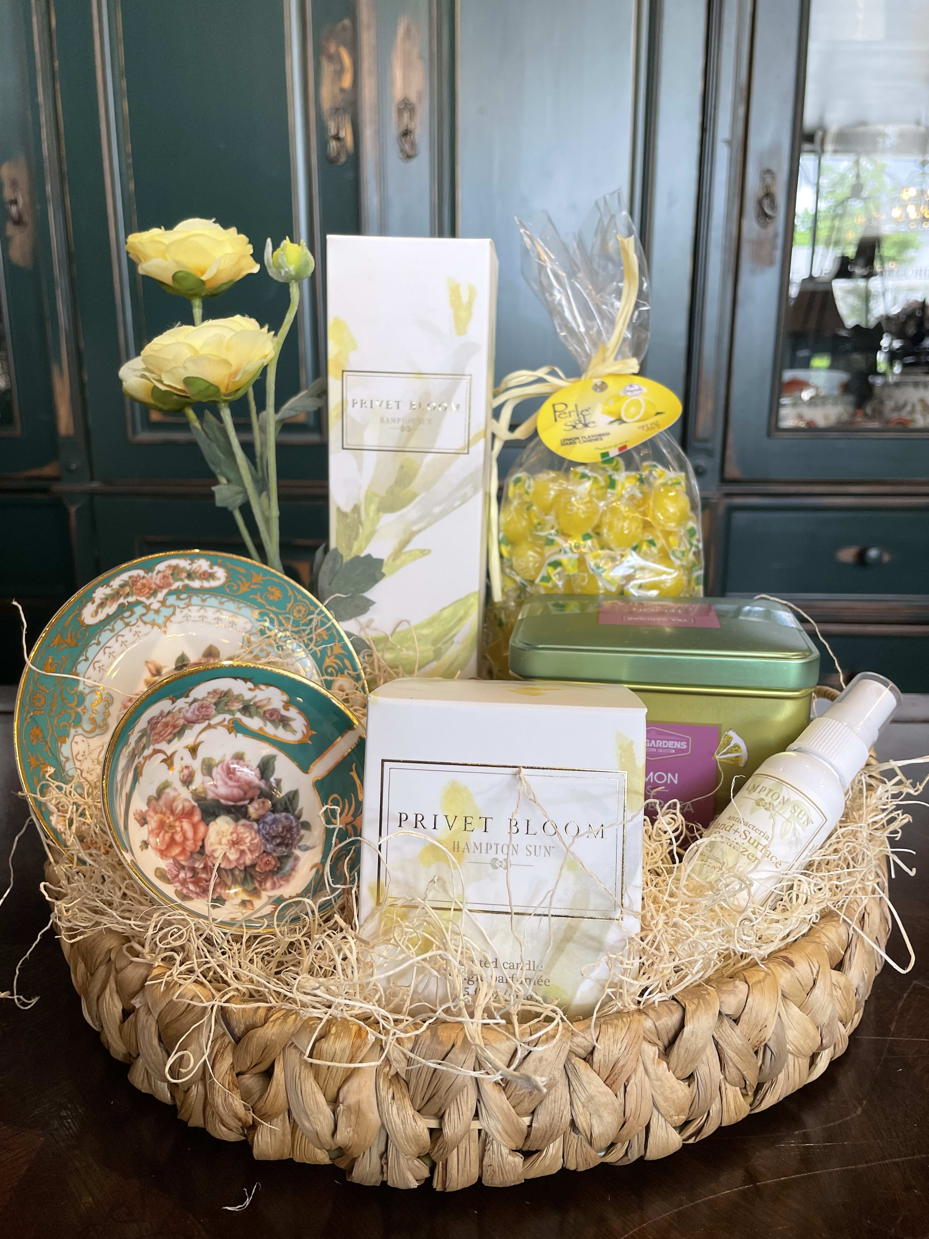 Gift basket with yellow flowers, decorative plates, and assorted packaged items