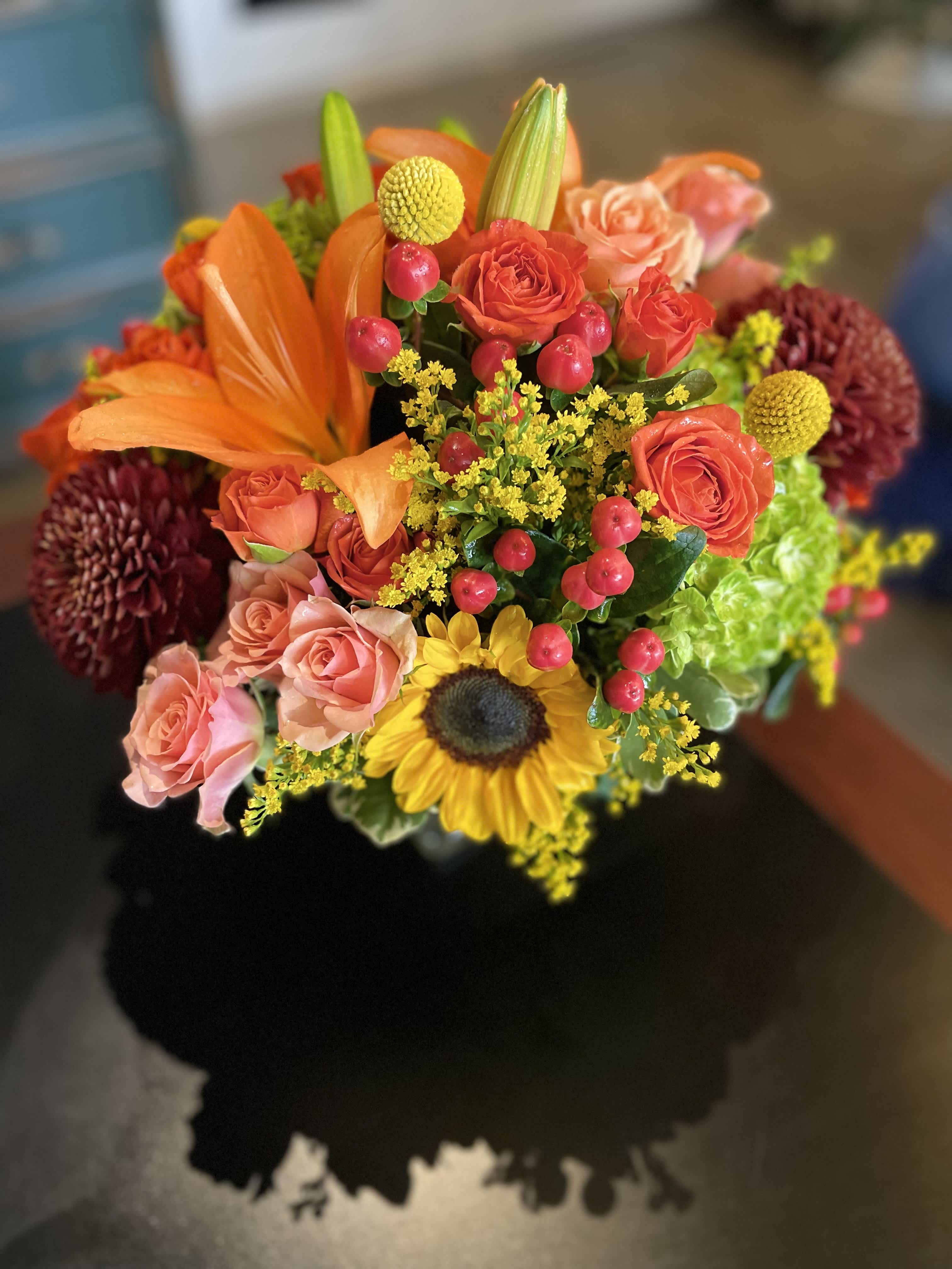 Mixed bouquet with orange lilies, coral roses, and a sunflower