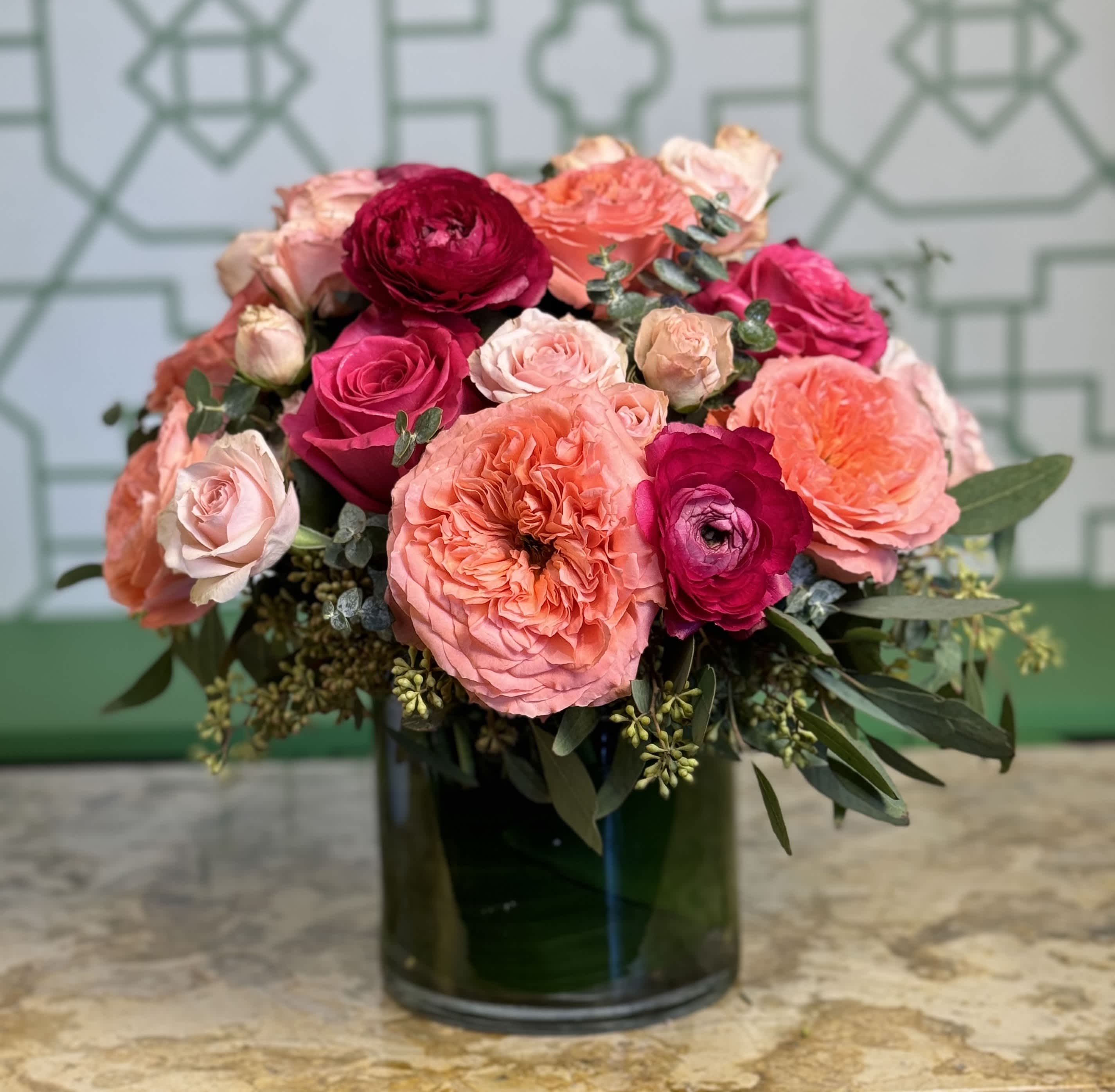 Pink and coral roses arranged in a dark glass vase