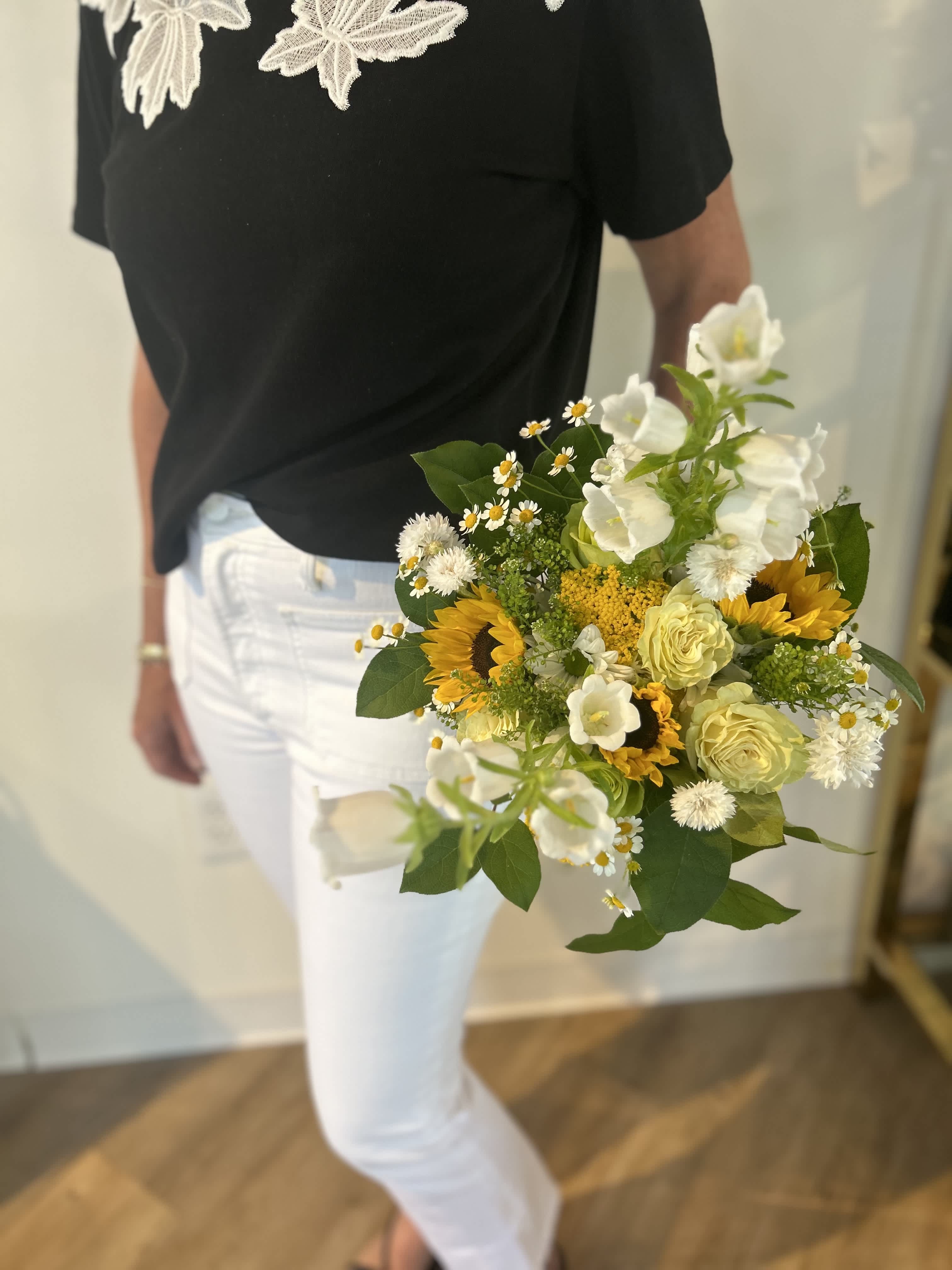 Handheld bouquet with sunflowers, white blooms, and pale yellow roses