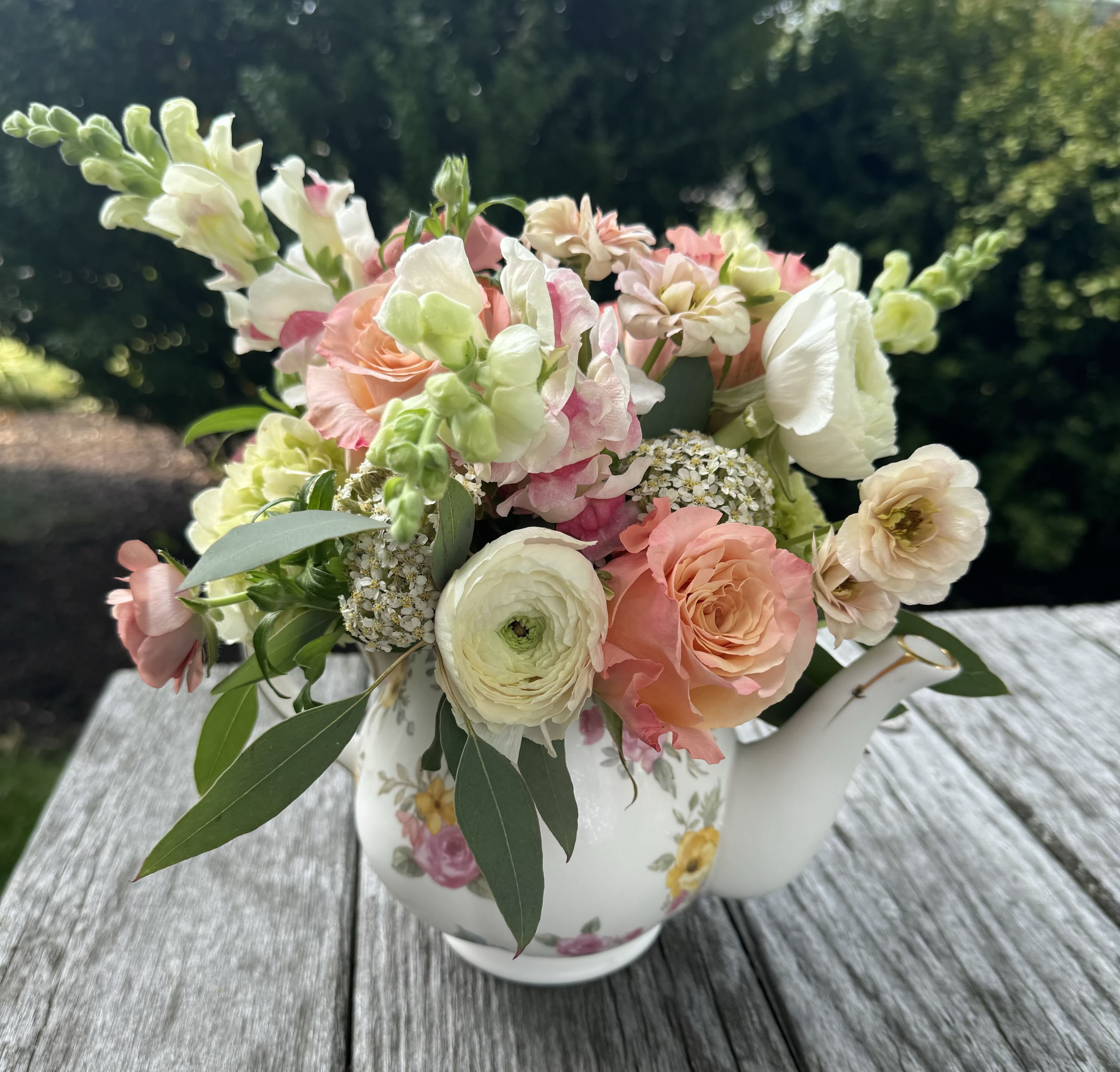 Pastel bouquet in a floral teapot vase