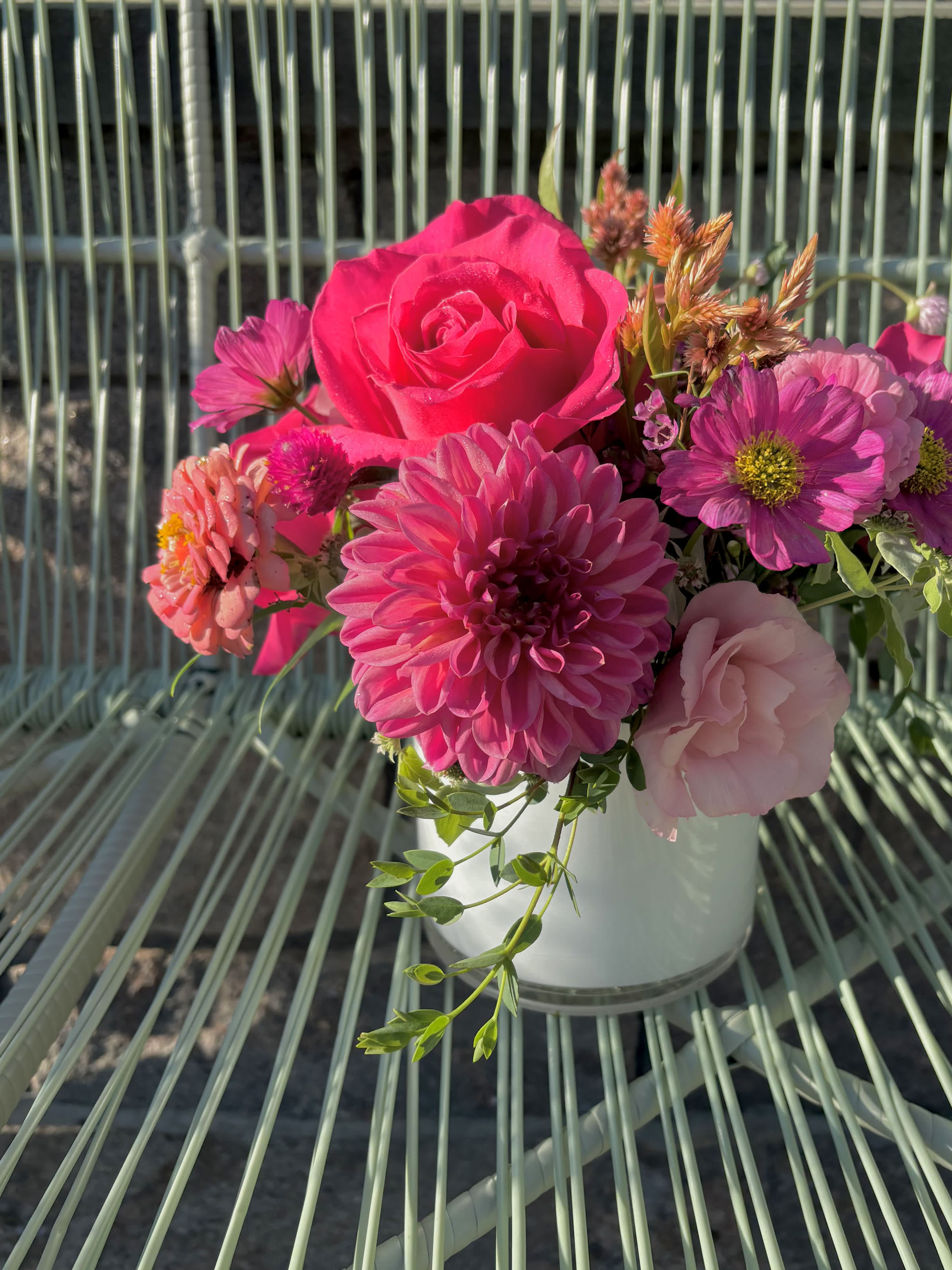 Pink and magenta flowers arranged in a white vase