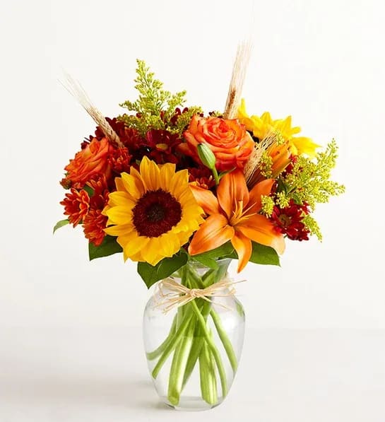 Sunflower and orange lily bouquet in a clear glass vase