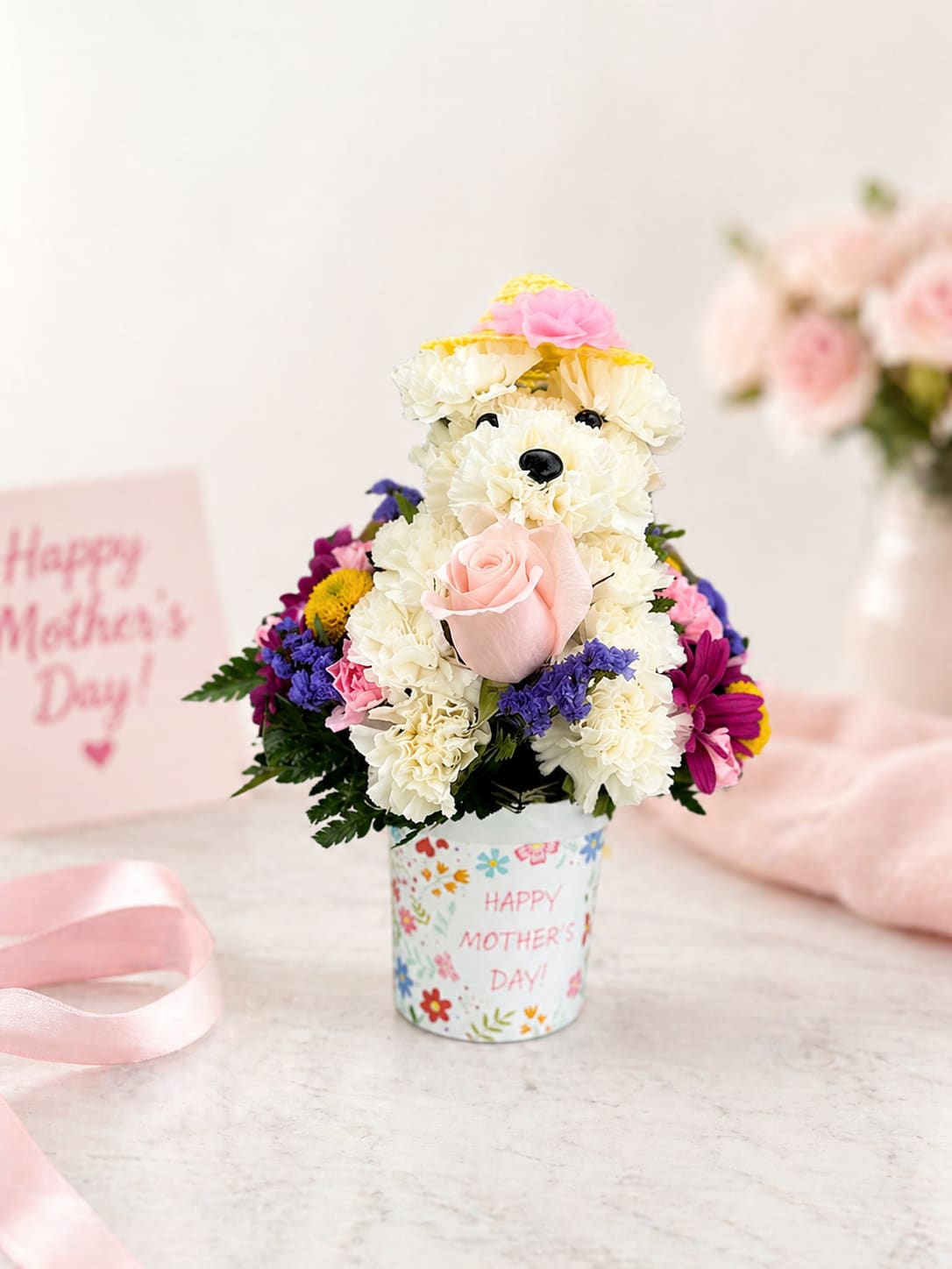 Mother’s Day Puppy Love Arrangement – Same Day Delivery Houston - Looking for a unique Mother’s Day gift that stands out? Our Mother’s Day Puppy Love Arrangement is one of the most memorable floral designs you can send in Houston. Handcrafted to resemble a cute puppy, this arrangement combines fresh carnations, roses, and vibrant seasonal flowers in a keepsake Mother’s Day container.  This design is perfect for moms, grandmothers, or anyone who loves something creative and heartfelt. It’s not just flowers, it’s a conversation piece that makes people smile the second it arrives.  At Floral Concepts, we use only fresh, high-quality flowers sourced daily and design each arrangement by hand. Every order is carefully prepared and delivered to ensure it arrives looking full, clean, and photo-ready.  We offer same day flower delivery in Houston and surrounding areas, making it easy to send something special even last minute.  Why this arrangement works: • Unique puppy design customers remember • Perfect for Mother’s Day gifting • Hand-designed with fresh flowers • Same day delivery available in Houston  Order now for guaranteed Mother’s Day delivery.