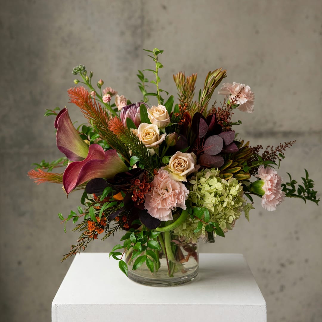 Mixed floral arrangement in a clear glass vase with pink and cream blooms