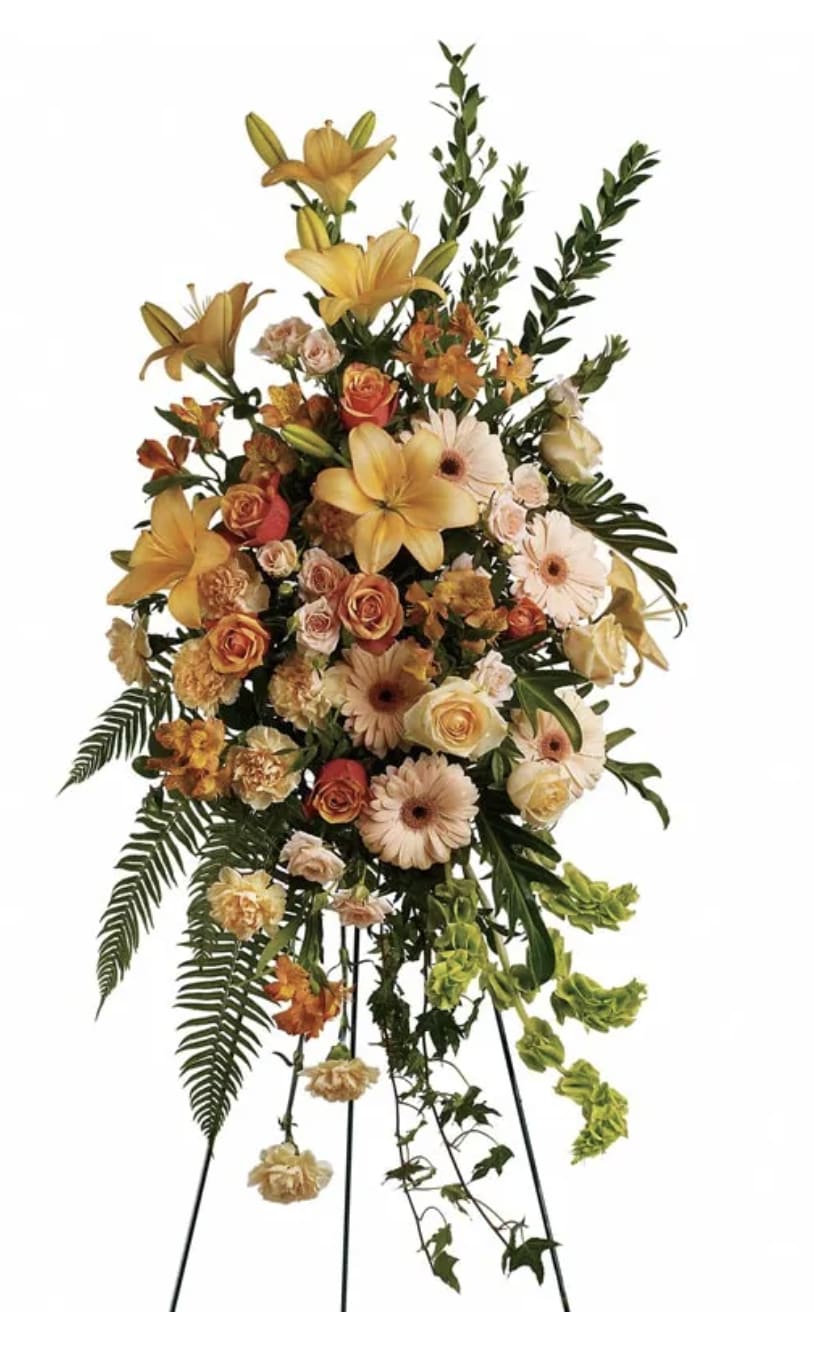 Tall standing floral spray with yellow lilies, peach roses, and pale gerberas