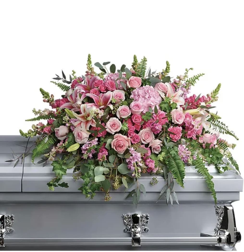 Pink floral casket spray with roses, lilies, and greenery