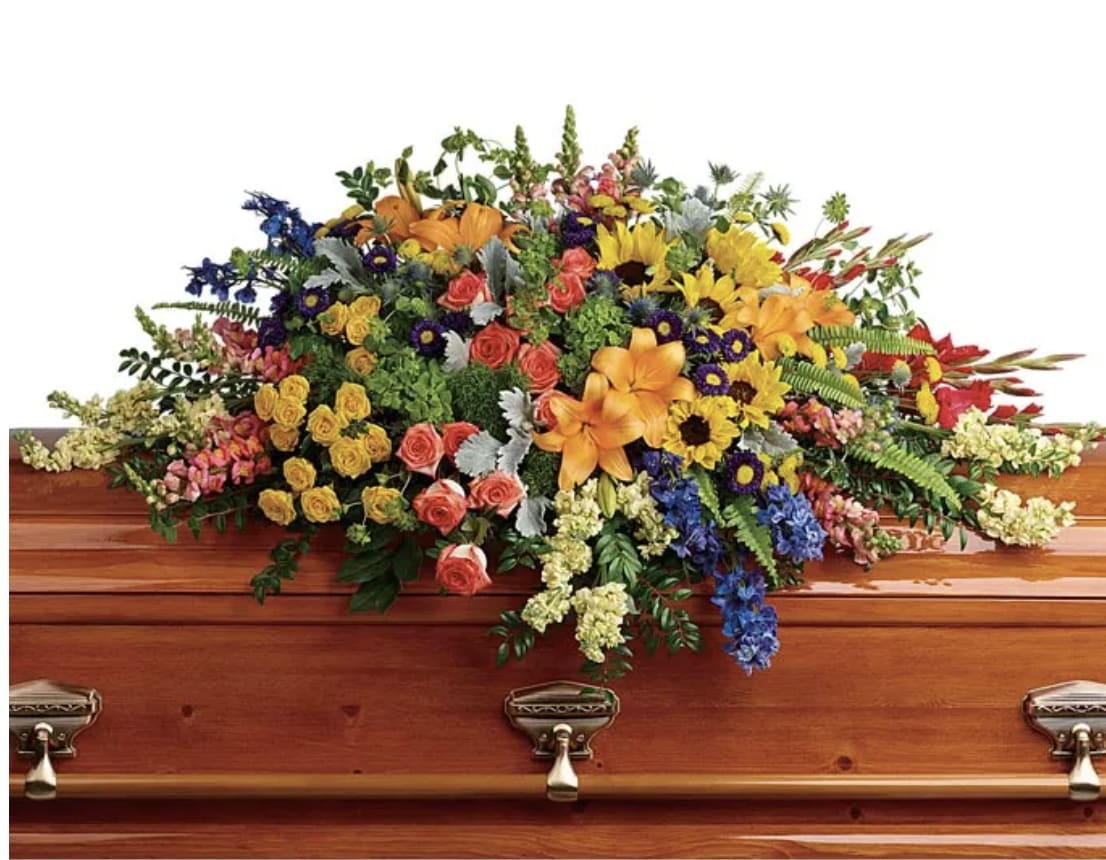 Colorful floral casket spray on a wooden coffin