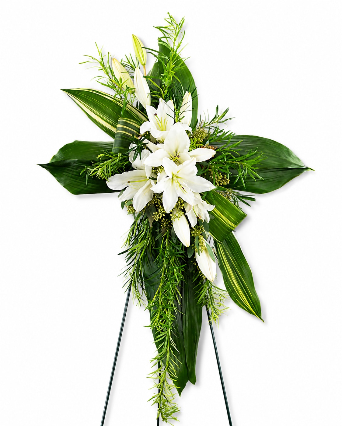 Pure White  Cross - White lilies take center stage in this Greenery Cross sympathy arrangement, their pure white blooms set against a bold cross-shaped framework of broad tropical leaves and trailing greenery. As a funeral or memorial standing spray, the vertical silhouette on a floral easel gives it a ceremonial, respectful presence that communicates sympathy and quiet strength to the person you're honoring.  The design is formal and structured, with layered deep green foliage creating strong lines that frame the clustered lilies for high contrast and visual clarity. Finished on a support stand for stable display at services, the arrangement's restrained palette and elegant textures make it a timeless choice for expressing condolences and offering comfort to grieving family and friends.