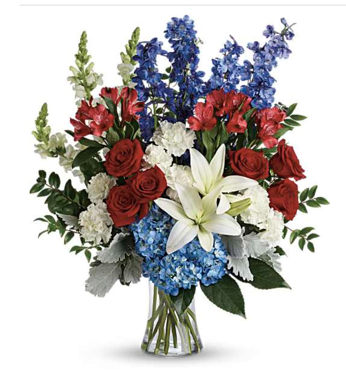 Honoring a Life with Vibrant Blooms - A dramatic upright arrangement that speaks with bold color and quiet dignity, perfect as a sympathy tribute or a romantic, patriotic statement. This flower arrangement for sympathy and funeral or for love and romance pairs red roses and red alstroemeria with white lilies and vivid blue hydrangeas and snapdragons, creating a striking trio of red, white, and blue that also suits Memorial Day, Fourth of July or a thoughtful Labor Day delivery.  The bouquet is styled in a clear glass vase with a full, upright composition and silver-toned foliage that lends a polished, slightly formal finish. Textures range from the velvety rose petals and smooth lily blooms to the clustered hydrangeas and vertical snapdragons, giving visual depth and a celebratory yet respectful presence on a mantel, altar, or bedside table.  Choose this arrangement when you want the recipient to feel deeply seen-whether you're honoring a life, saying "I love you," or marking a national remembrance. The clear vase makes care simple: keep water fresh and trim stems as needed to prolong bloom life.