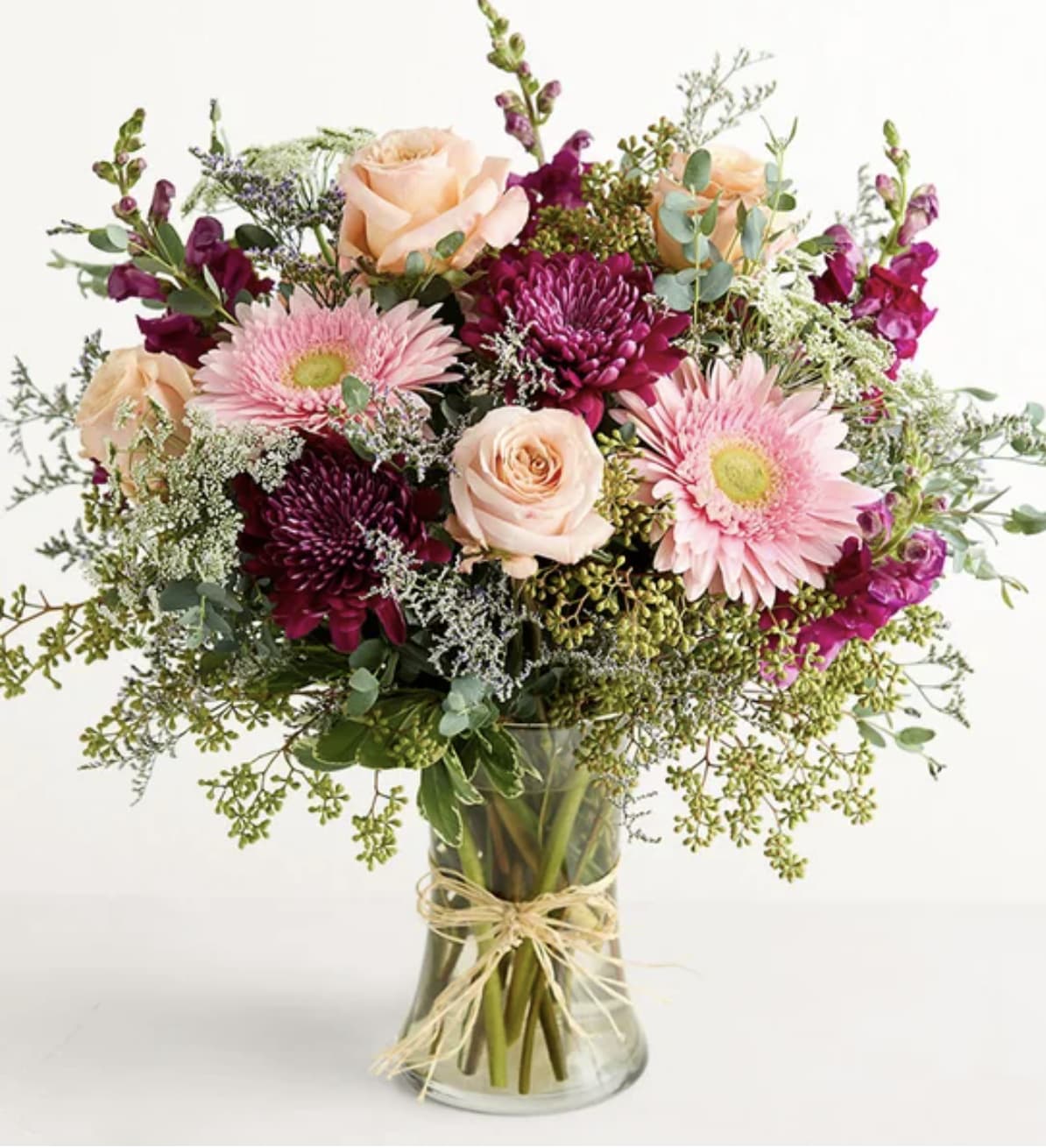 Mixed bouquet of pink and peach flowers in a clear glass vase
