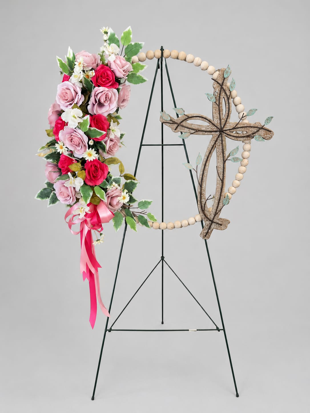 Floral cross wreath with pink roses and white daisies on a stand