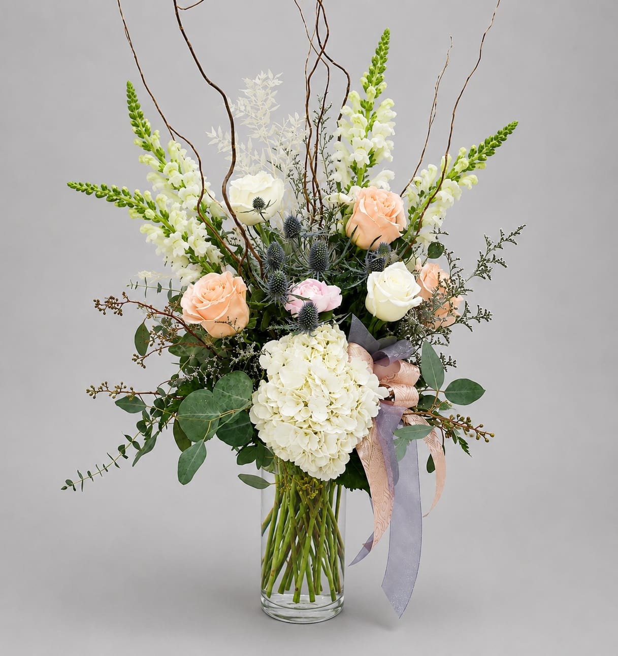 Tall bouquet of white and peach flowers in a clear glass vase