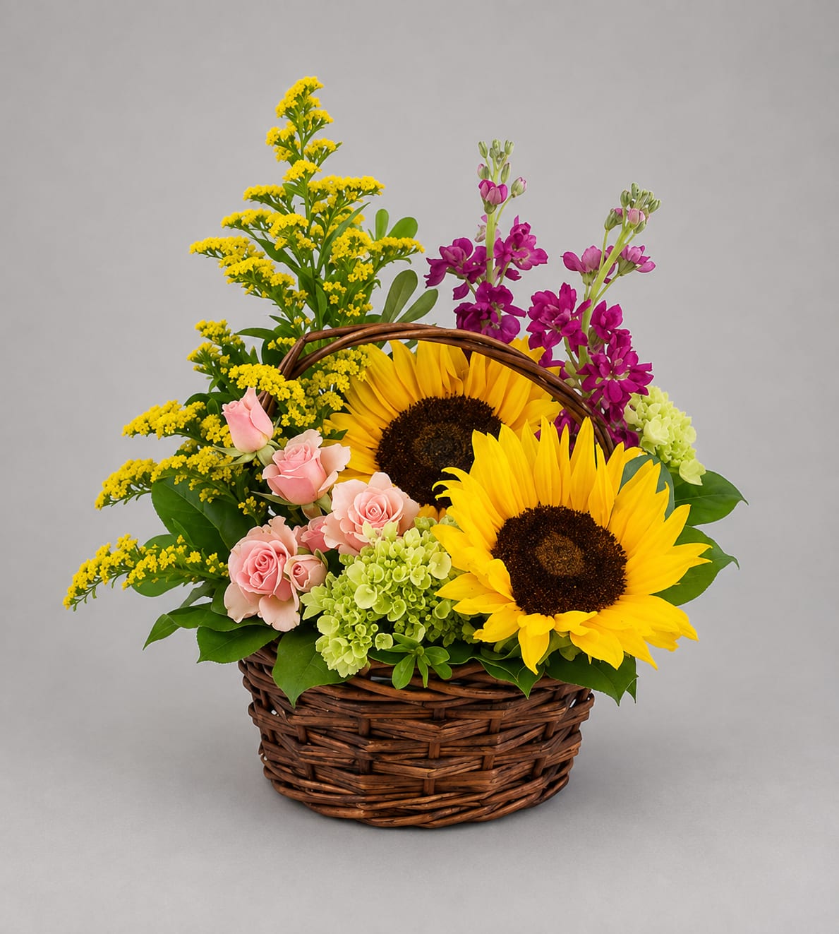 Basket arrangement with sunflowers, pink roses, and purple blooms