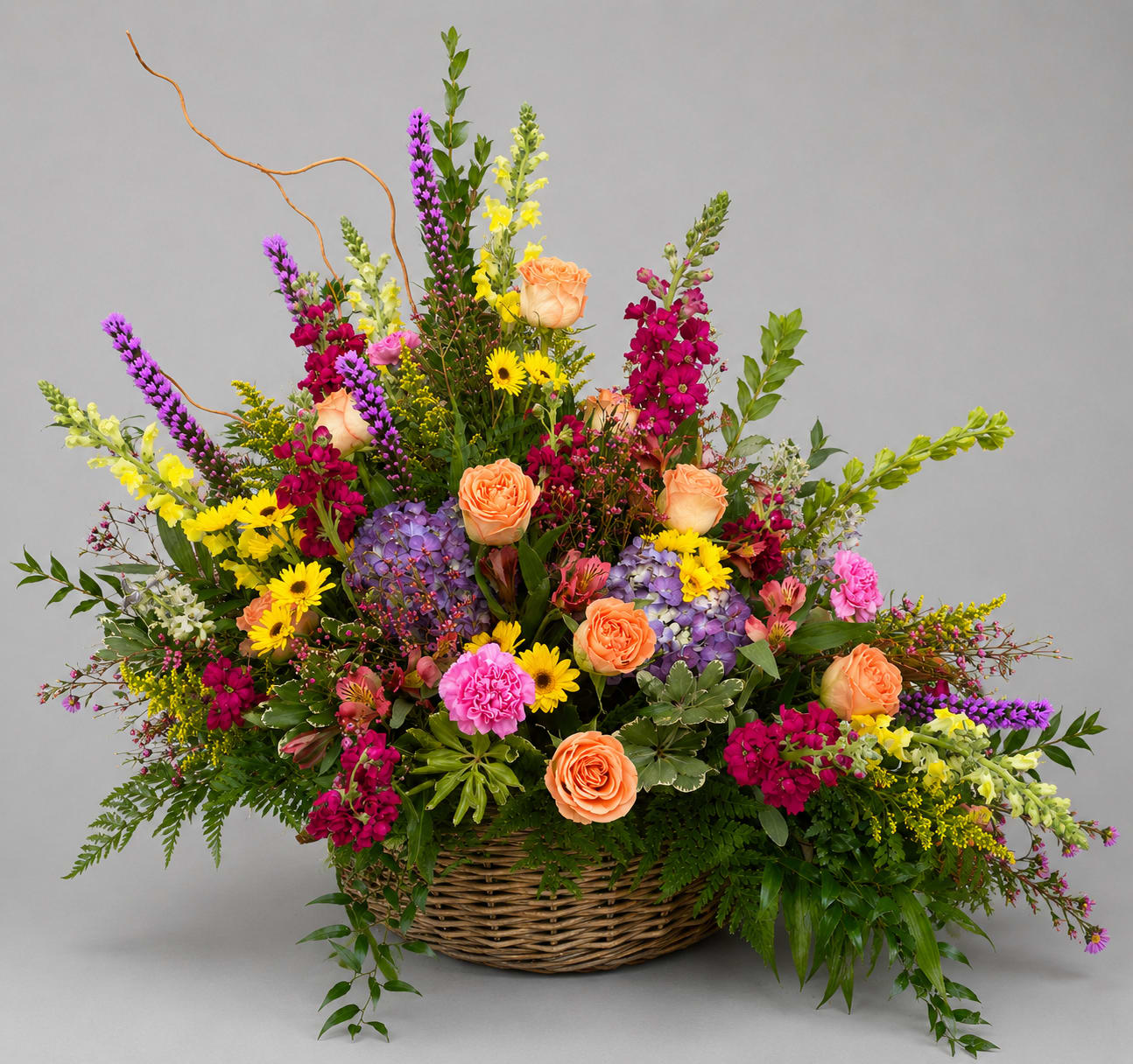 Large mixed flower arrangement in a wicker basket