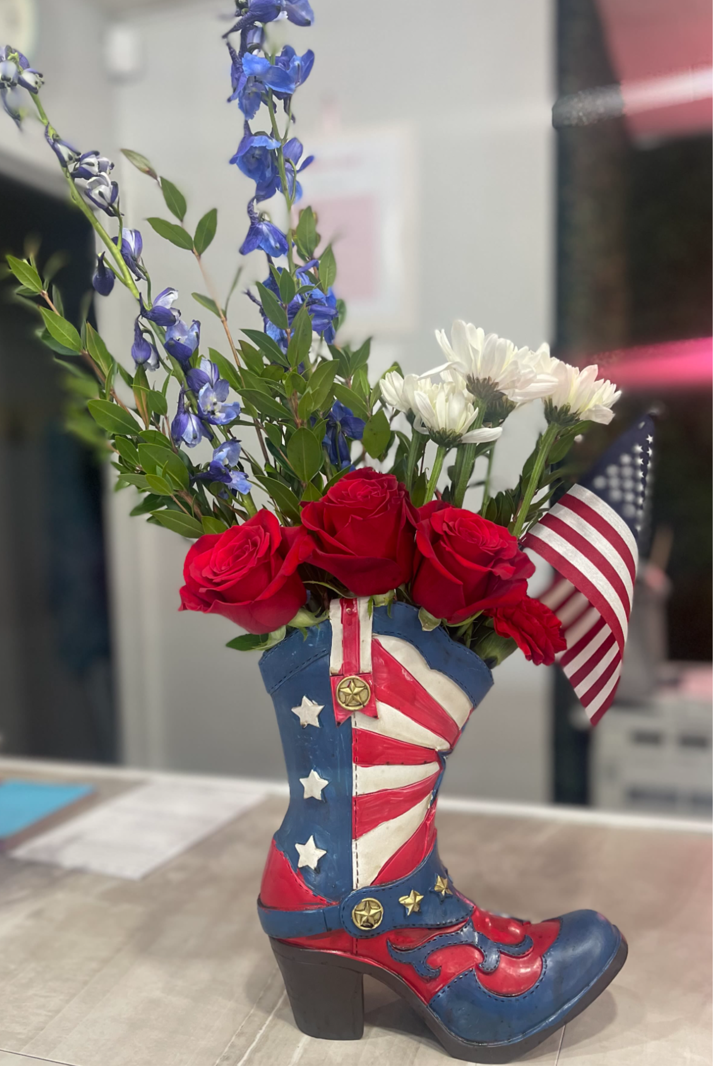 Red roses and white daisies arranged in a patriotic cowboy boot vase
