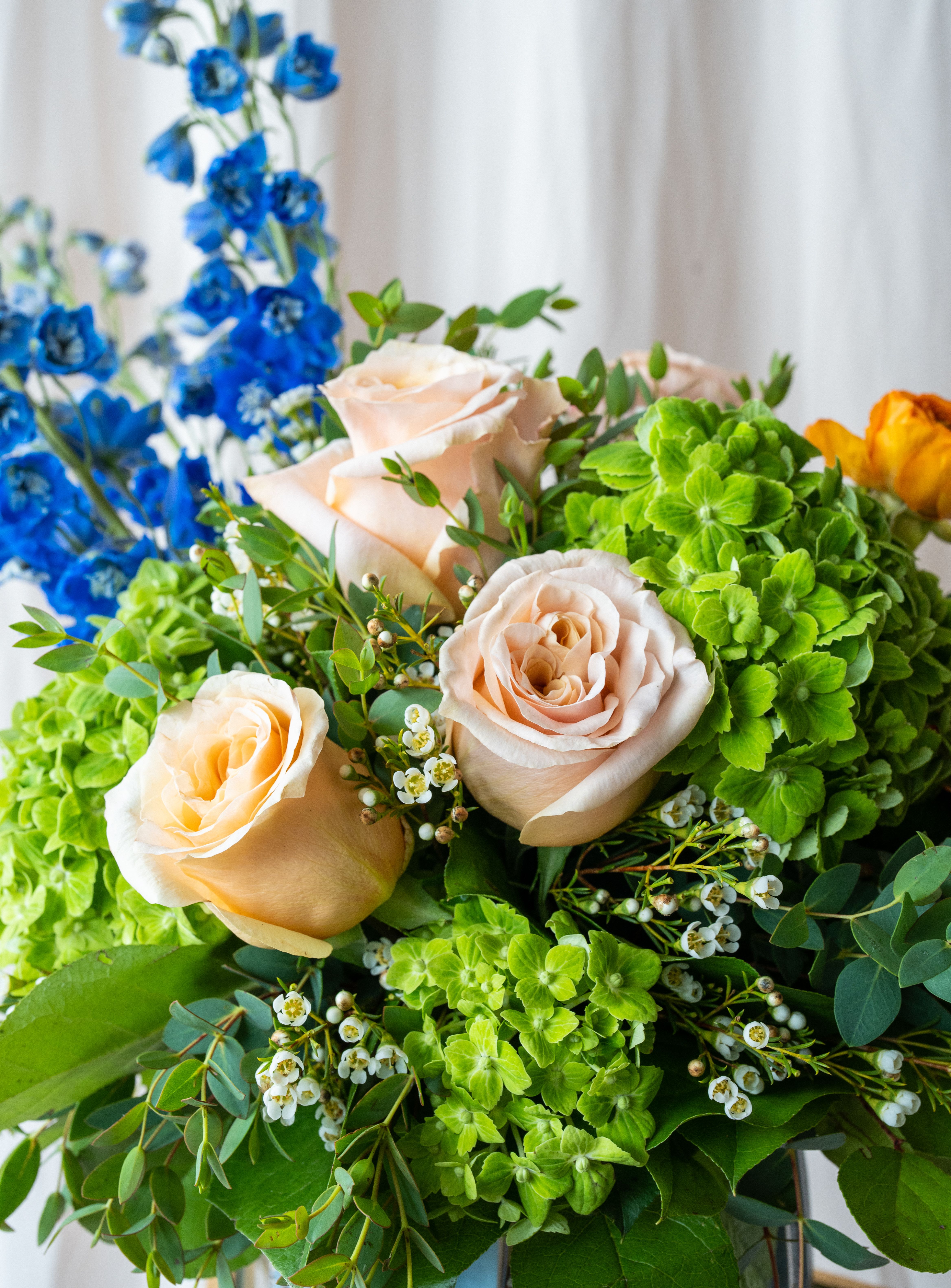 Bouquet of peach roses, green hydrangeas, and blue flowers