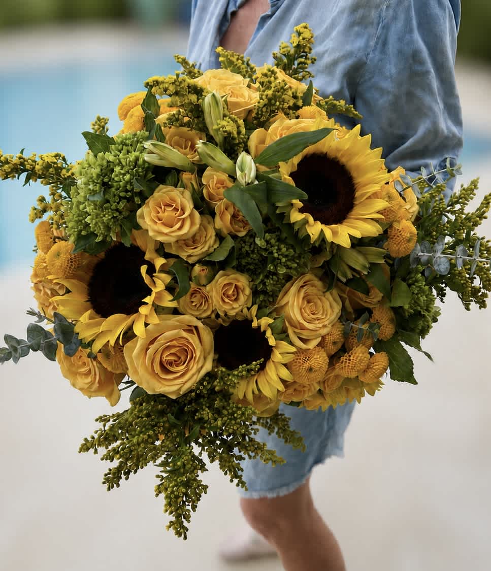 Large bouquet of yellow roses and sunflowers with green filler