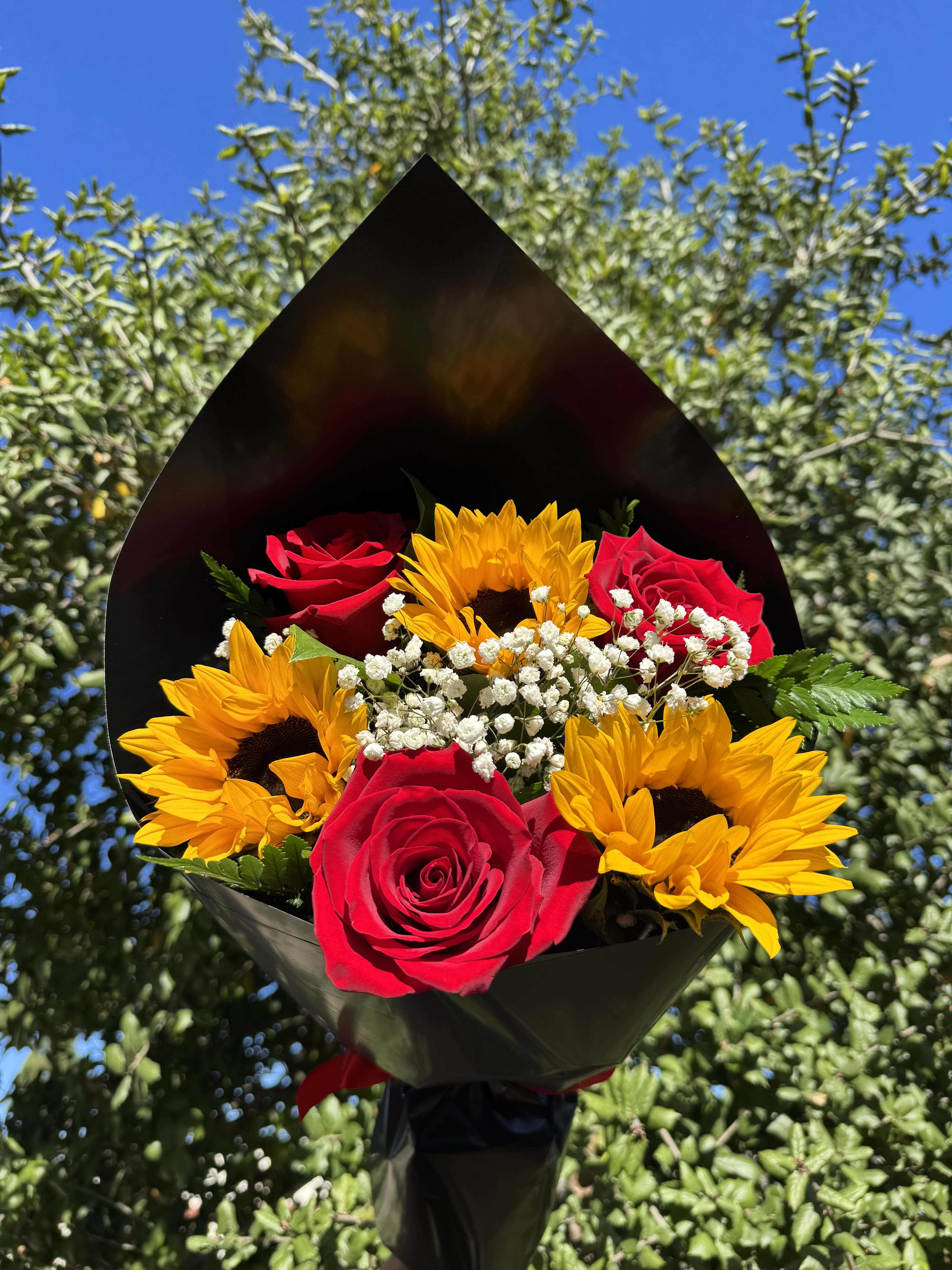 Bouquet of red roses and yellow sunflowers in black wrap