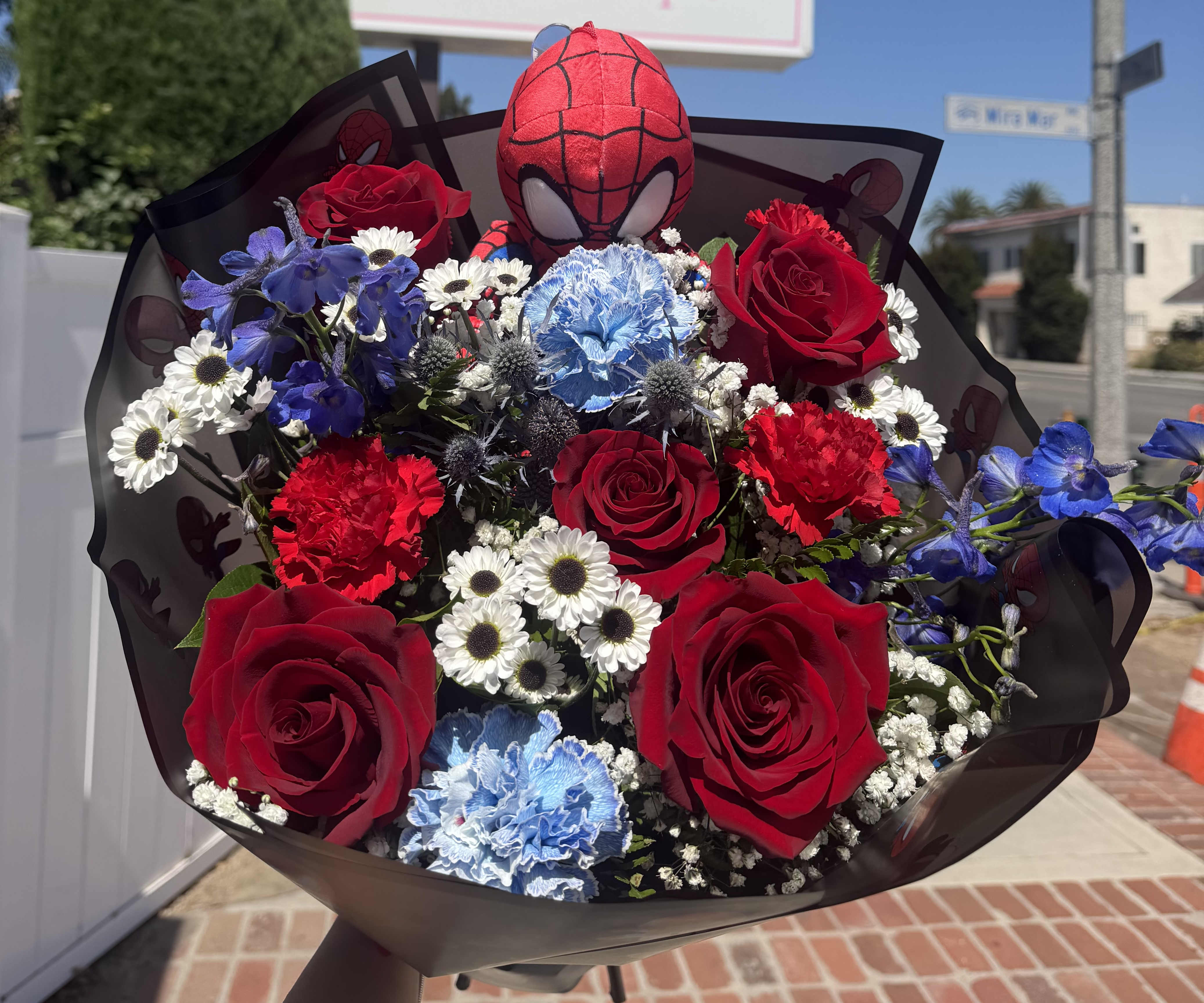 Bouquet of red roses, blue carnations, and white daisies with a Spider-Man plush