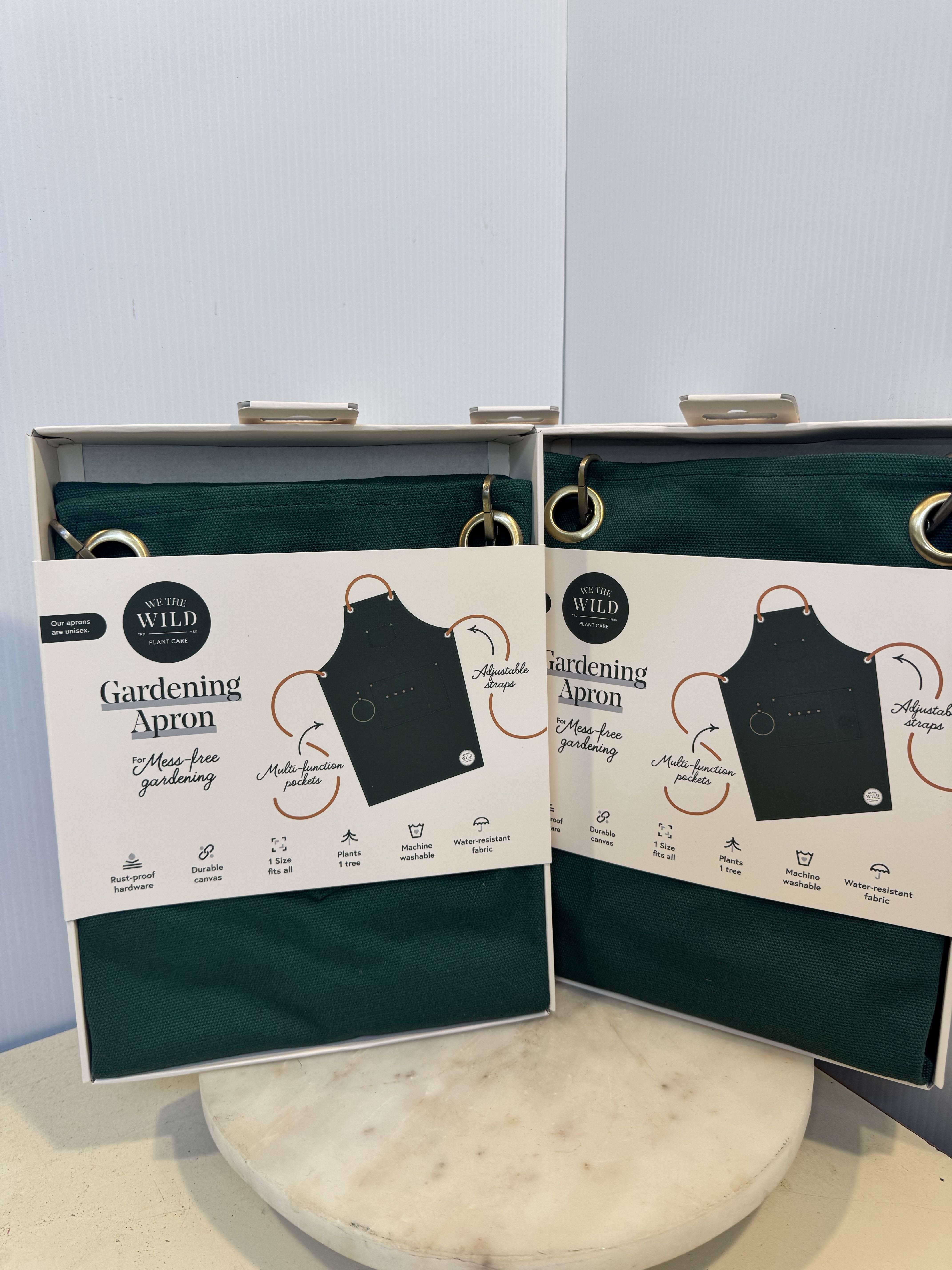 Two boxed green gardening aprons on a table