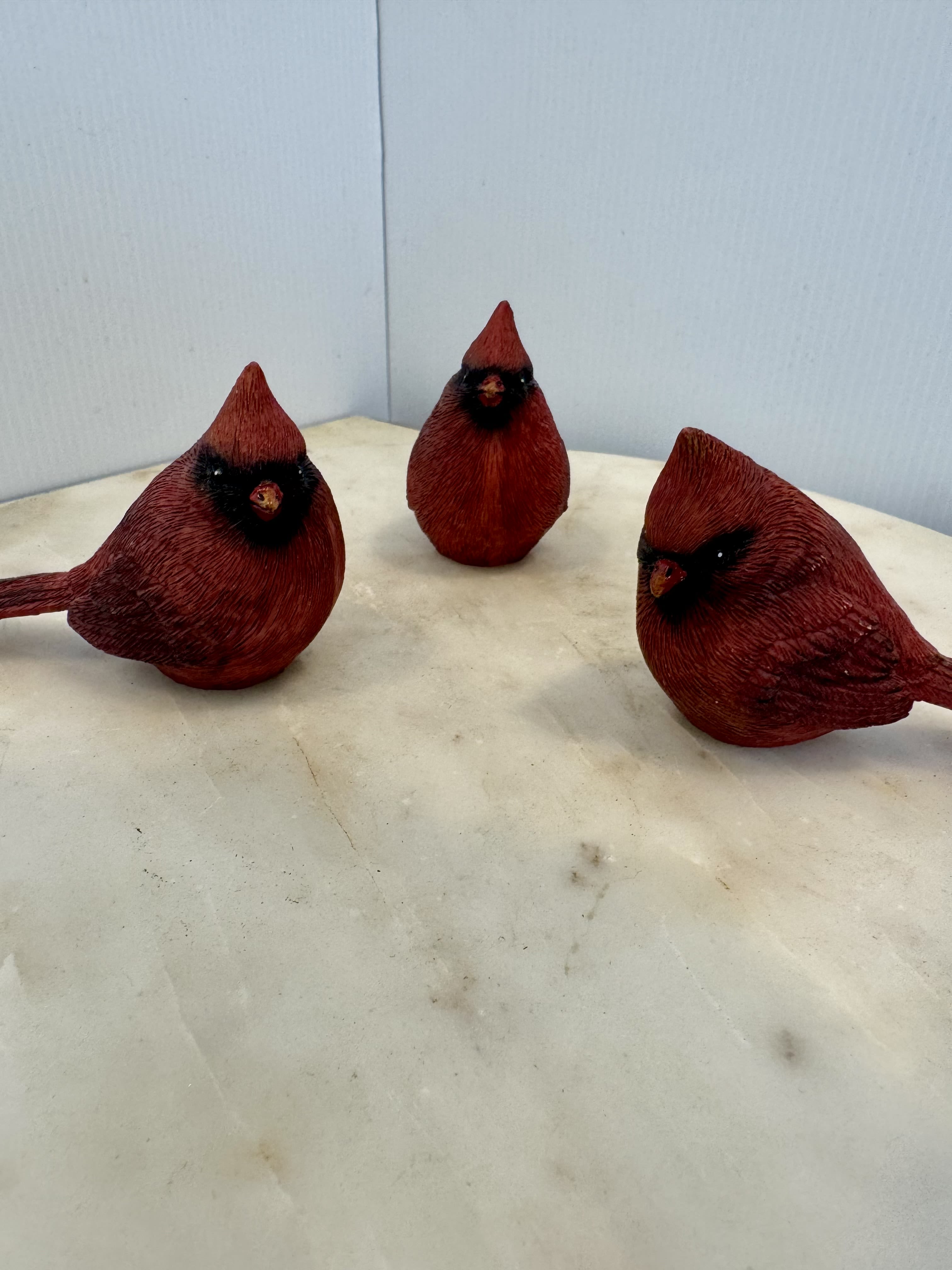 Three red decorative bird figurines on a light surface
