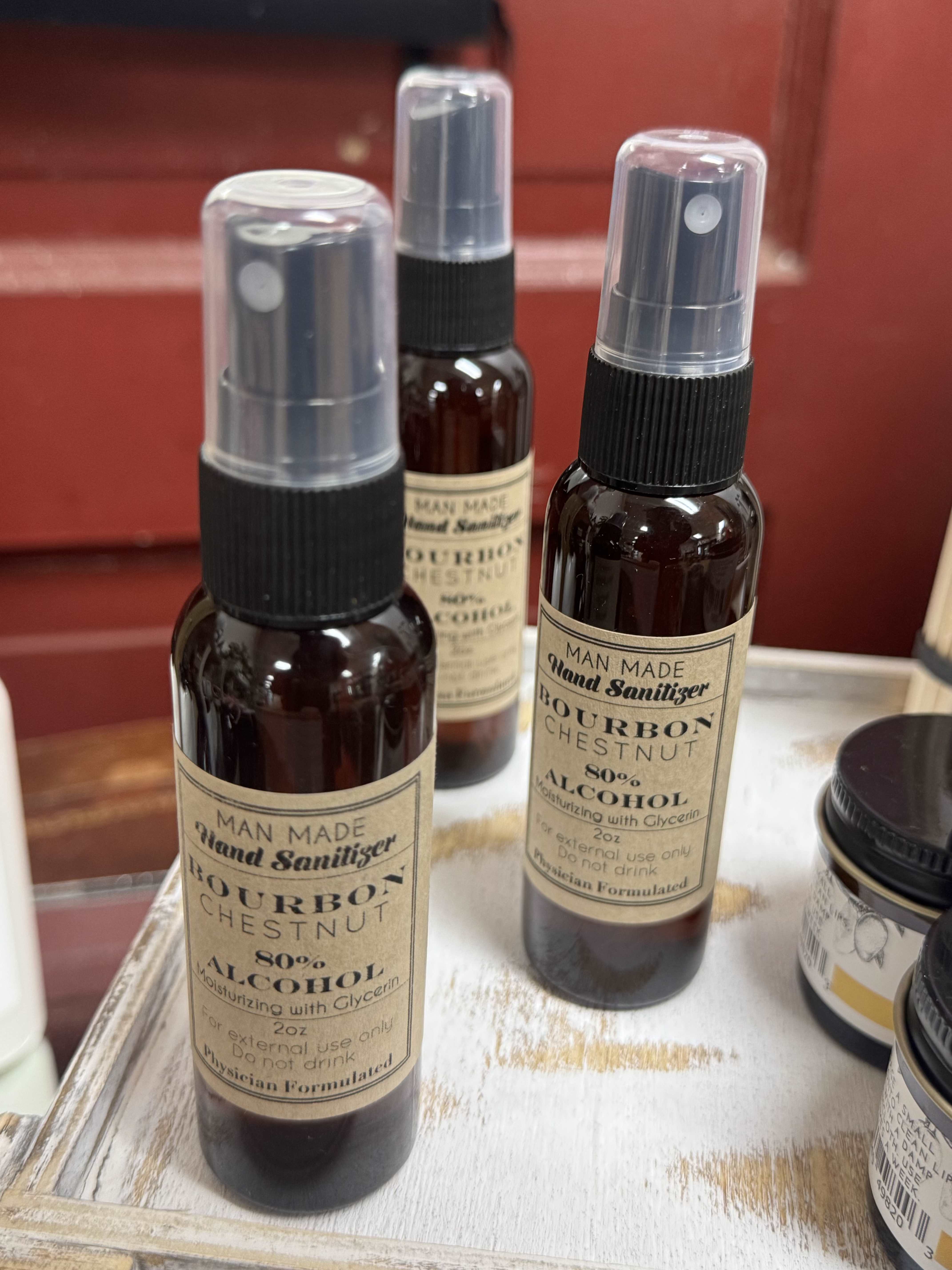 Three spray bottles of bourbon chestnut hand sanitizer on a tray
