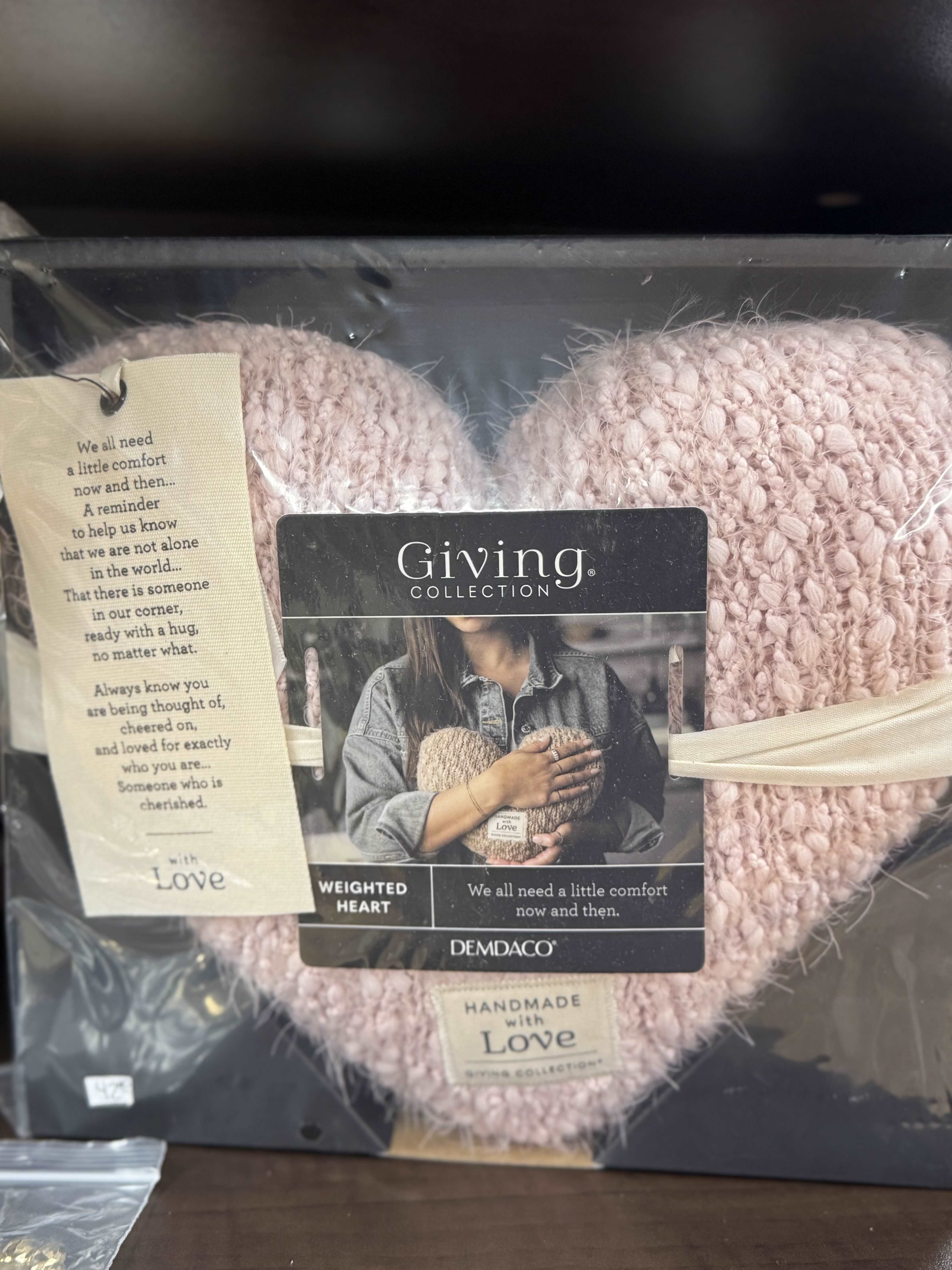 Pink knitted heart-shaped gift in a box with a comfort message tag