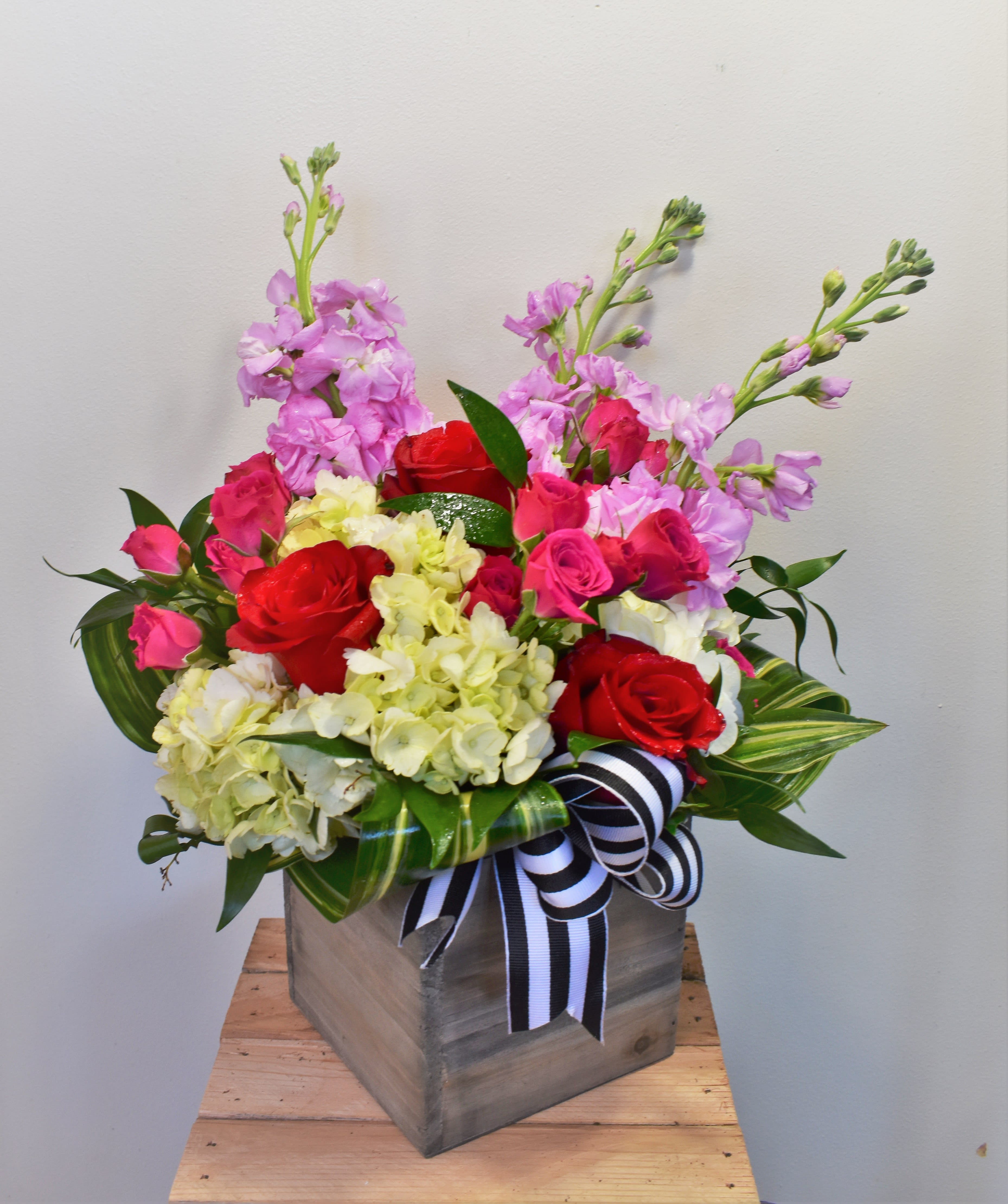 Pink and red roses with pale hydrangeas in a wooden box