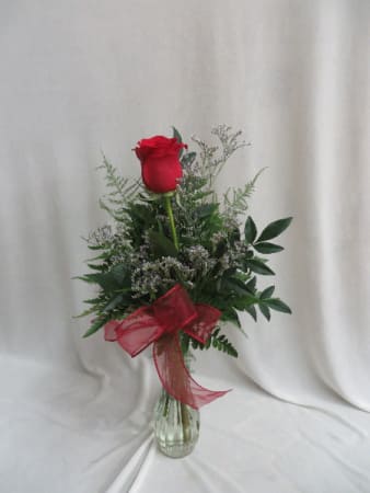 Single red rose arrangement in a clear glass vase with a red ribbon